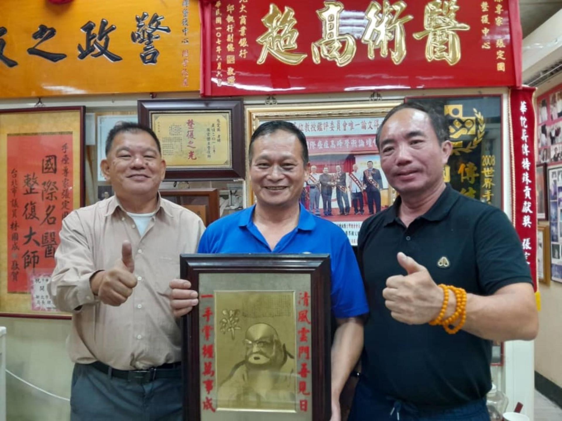 台湾中华古传手法研究委员会理事长张定国（中）与砂中医研究者陈中兴（左）及世界国际健康管理学会新加坡总会会长朱立信（右）合影。