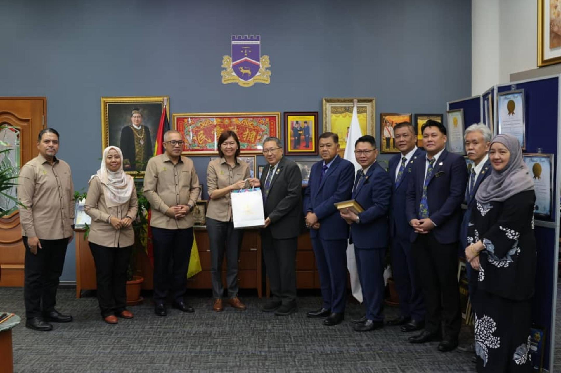 古晋南市市长拿督黄鸿圣（左5）与来自霹雳州行政议员的黄诗情（左4）互赠纪念品。