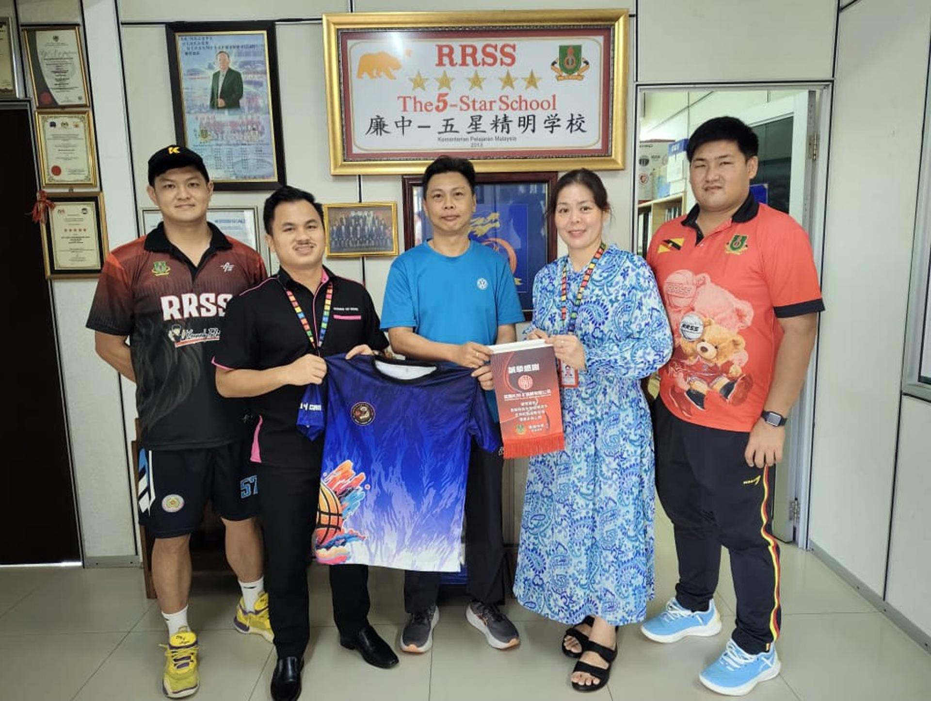 旺鼎Plan B海鲜有限公司王良贵先生移交球衣予廉律中学江佩娟校长，前排右2为联课副校长康亚雄，后排右2为联课副校长助理李世豪、左1为篮球校队林咸俊教练和球员们。