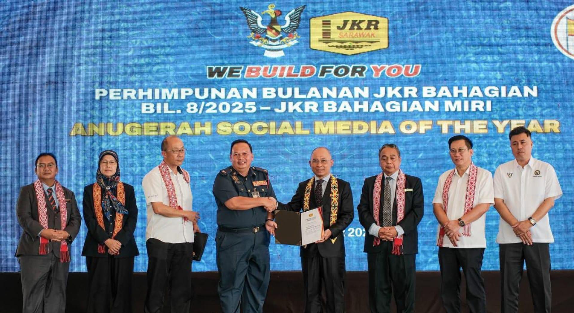 罗东消拯局局长亨利（左4）从砂公共工程局局长拿督阿都卡西迪手中接过“年度社媒支持者奖” 。