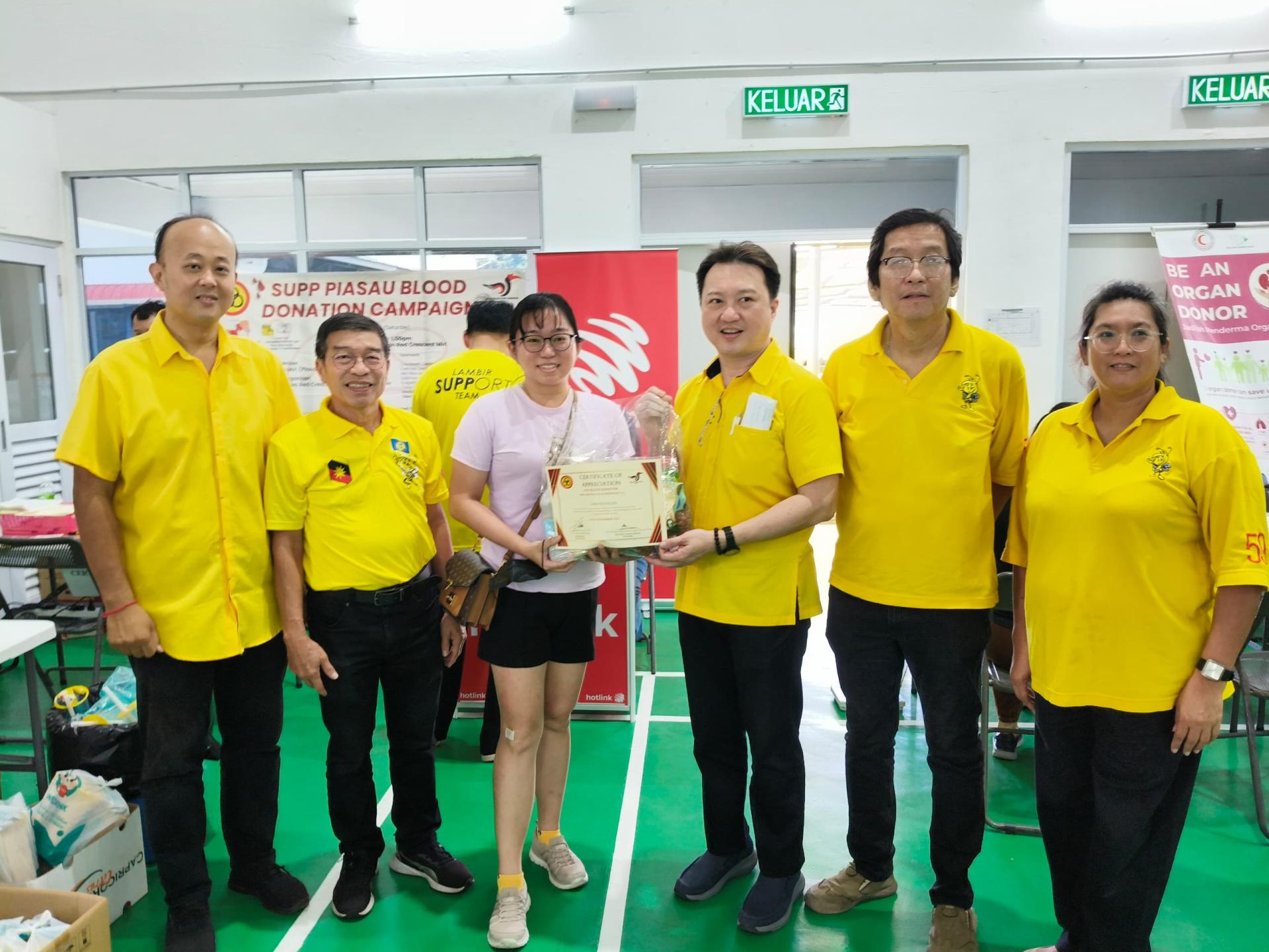 砂人联党卑尔骚支部秘书兼美里市议员谢家樑（右3）赠品及证书予一名成功捐血者。