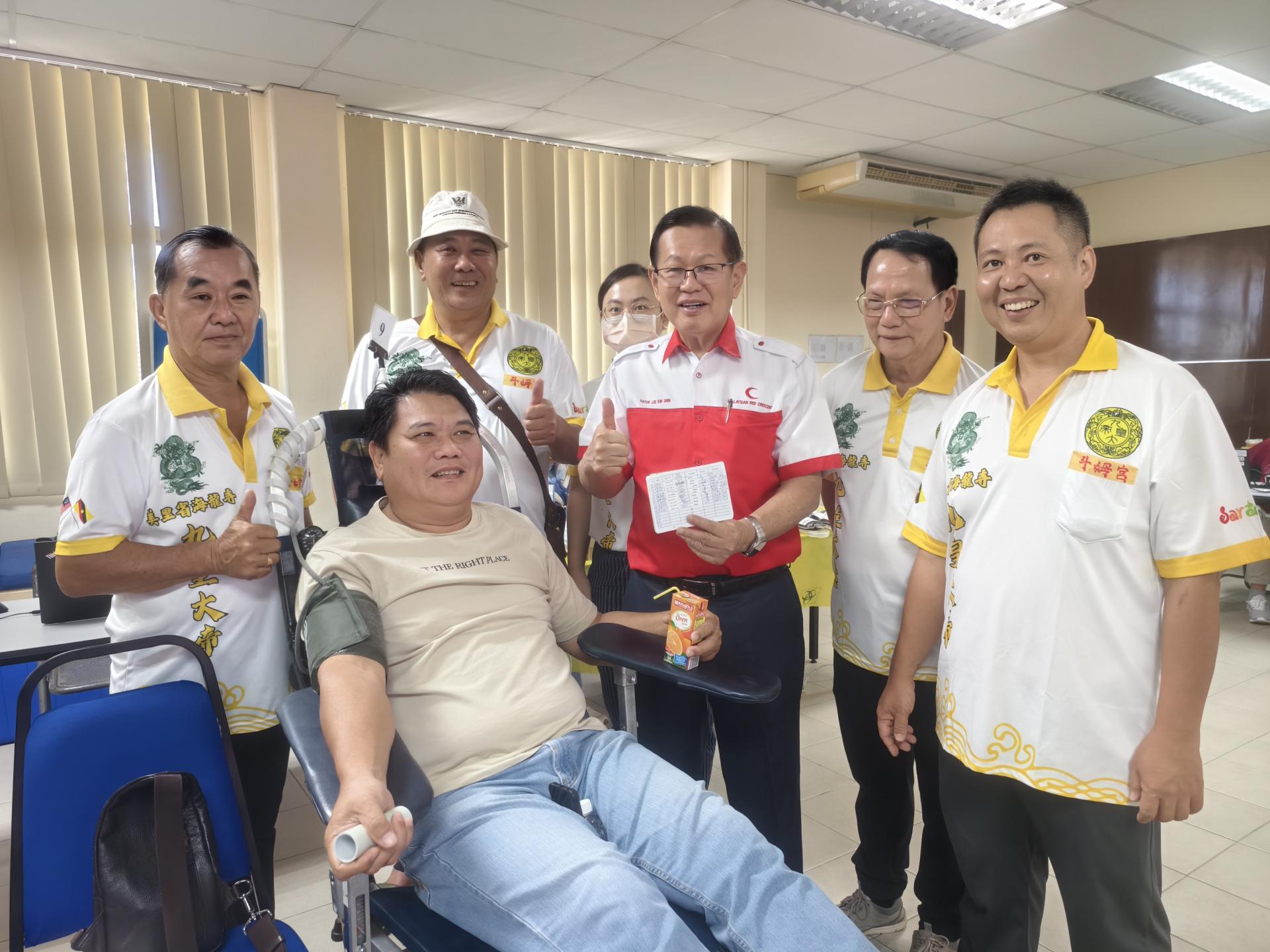 砂交通部长兼美里红新月会顾问拿督斯里李景胜（中）与美里省海龙成员和捐血超过80次的热心人士合影。