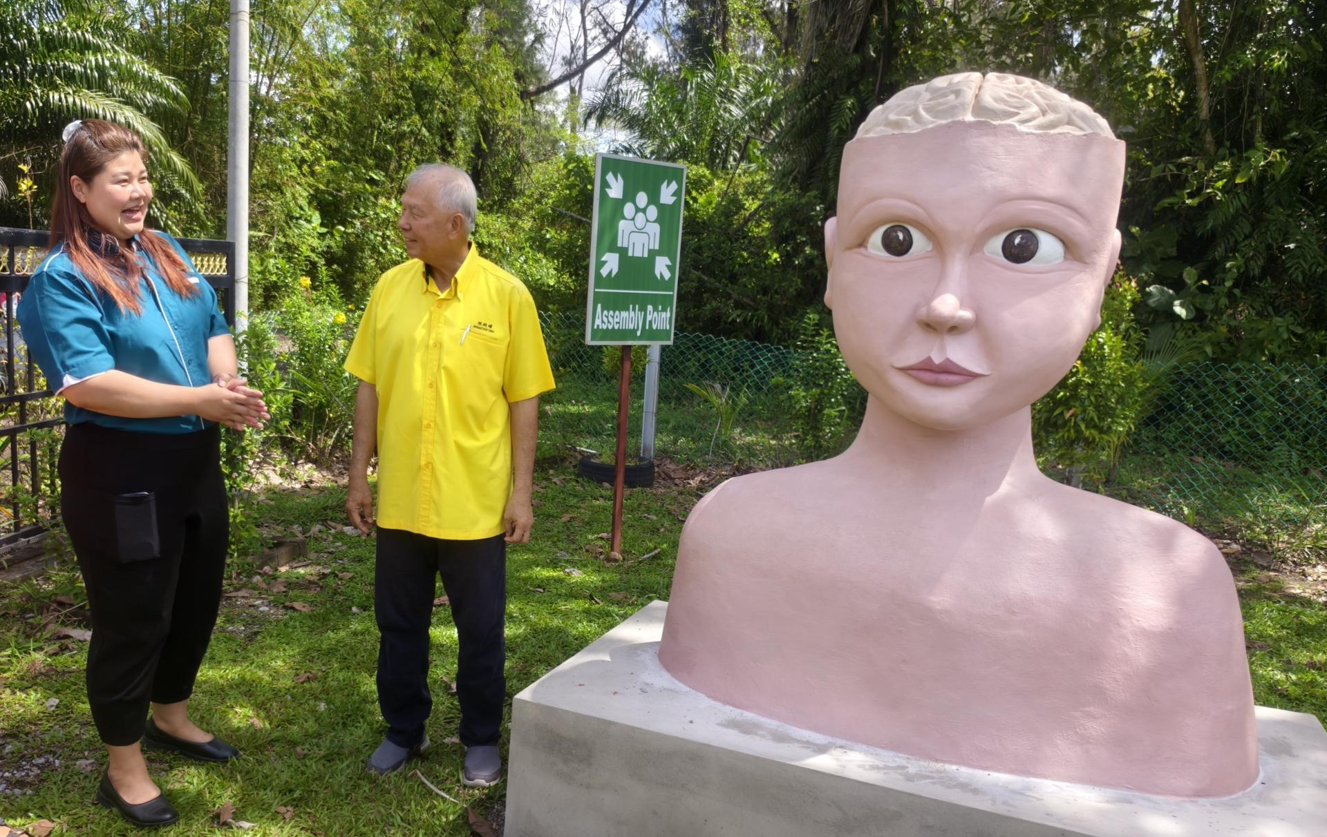 美里唯心乐园主席何逍凌（左）向砂旅游副部长兼卑尔骚区州议员拿督陈超耀介绍雕像的象征意义。