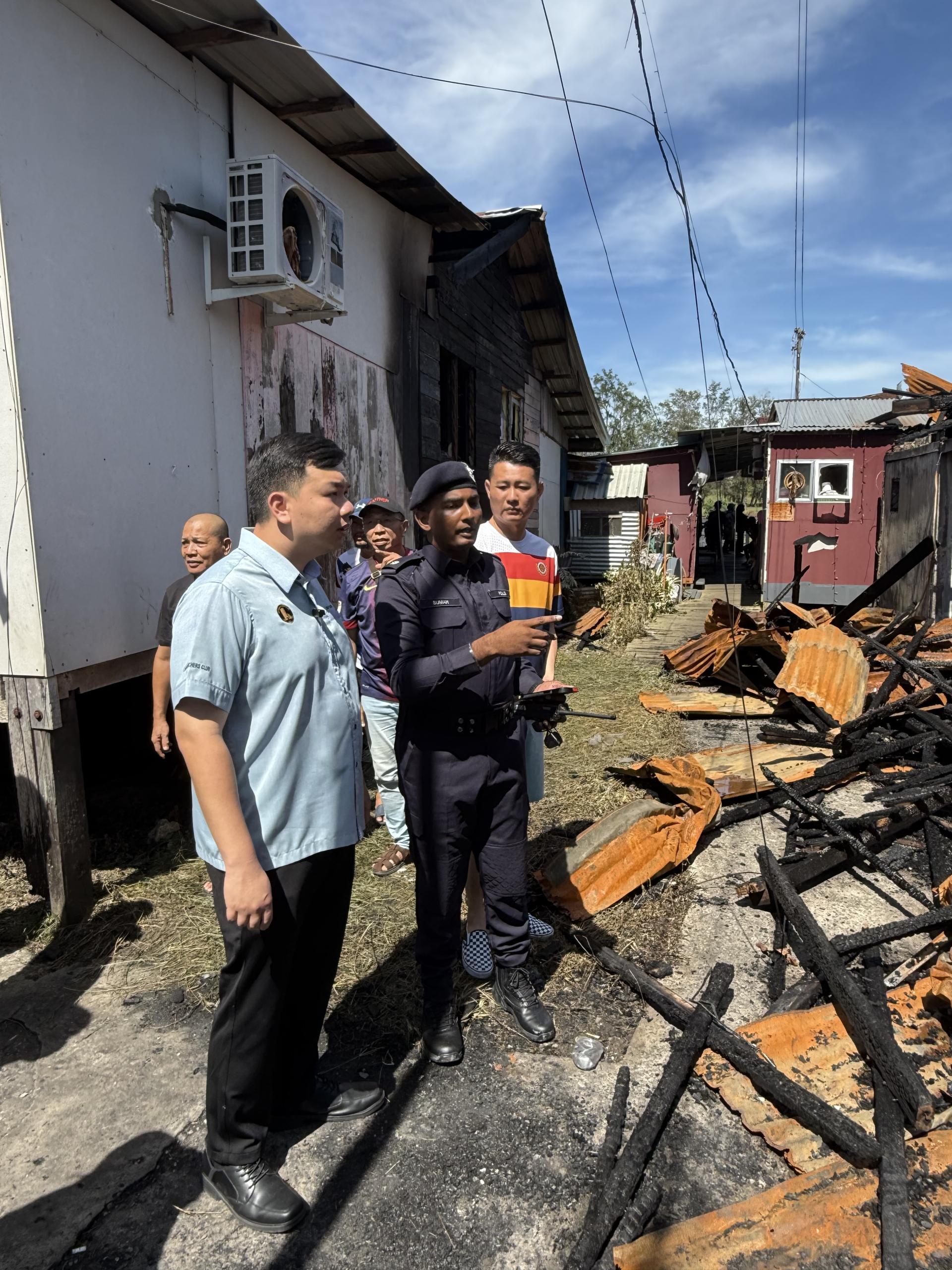 赵俊文国会议员（左1）和林思健（右）聆听苏曼警长在火灾现场给予的汇报时摄。