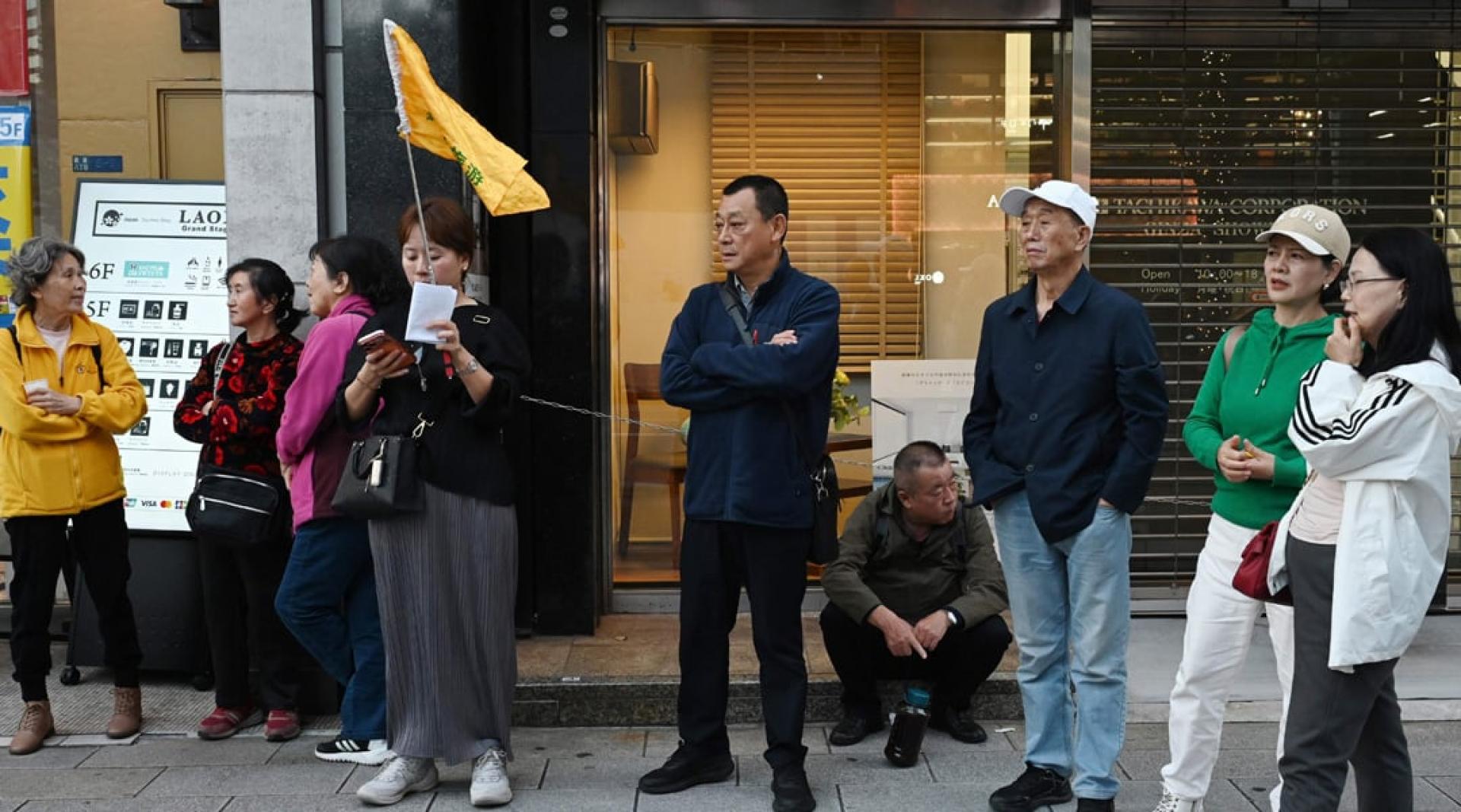 中国旅行团成员17日站在东京一家热门免税店外。