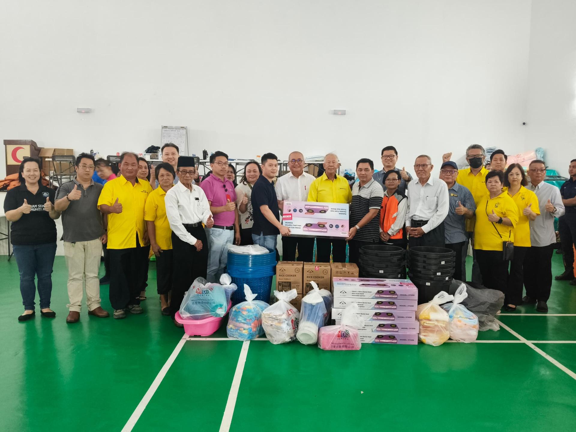 美里百货有限公司东主蔡荣耀（前排左8）在砂旅游部副部长拿督陈超耀（前排右6）及美里市长俞小珊（前排右7）见证下，移交生活用品予甘榜威尔乐斯村长鲁斯迪。