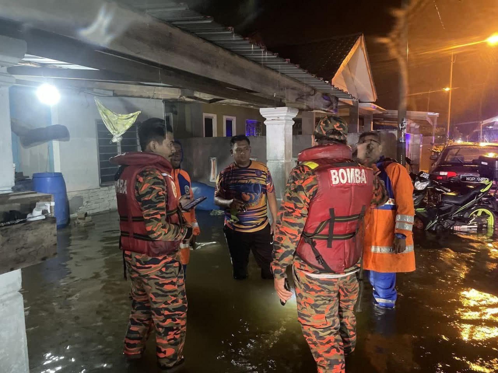 消拯员进入住宅区内，协助疏散受困水灾的居民，并将他们送往临时安置中心。