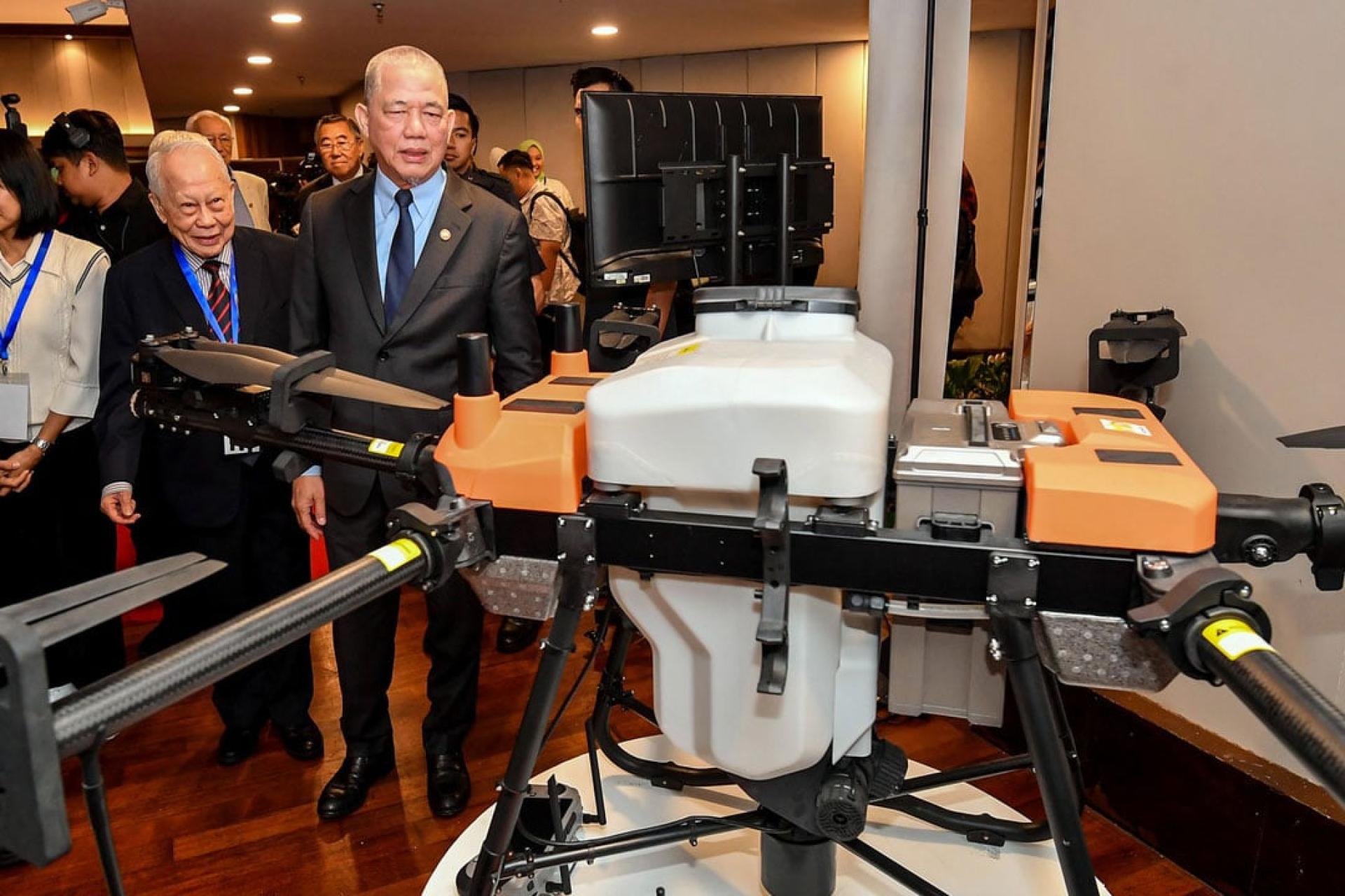 法迪拉（右）为2025年热带作物碳信用论坛主持开幕后，参观一个无人机展位。