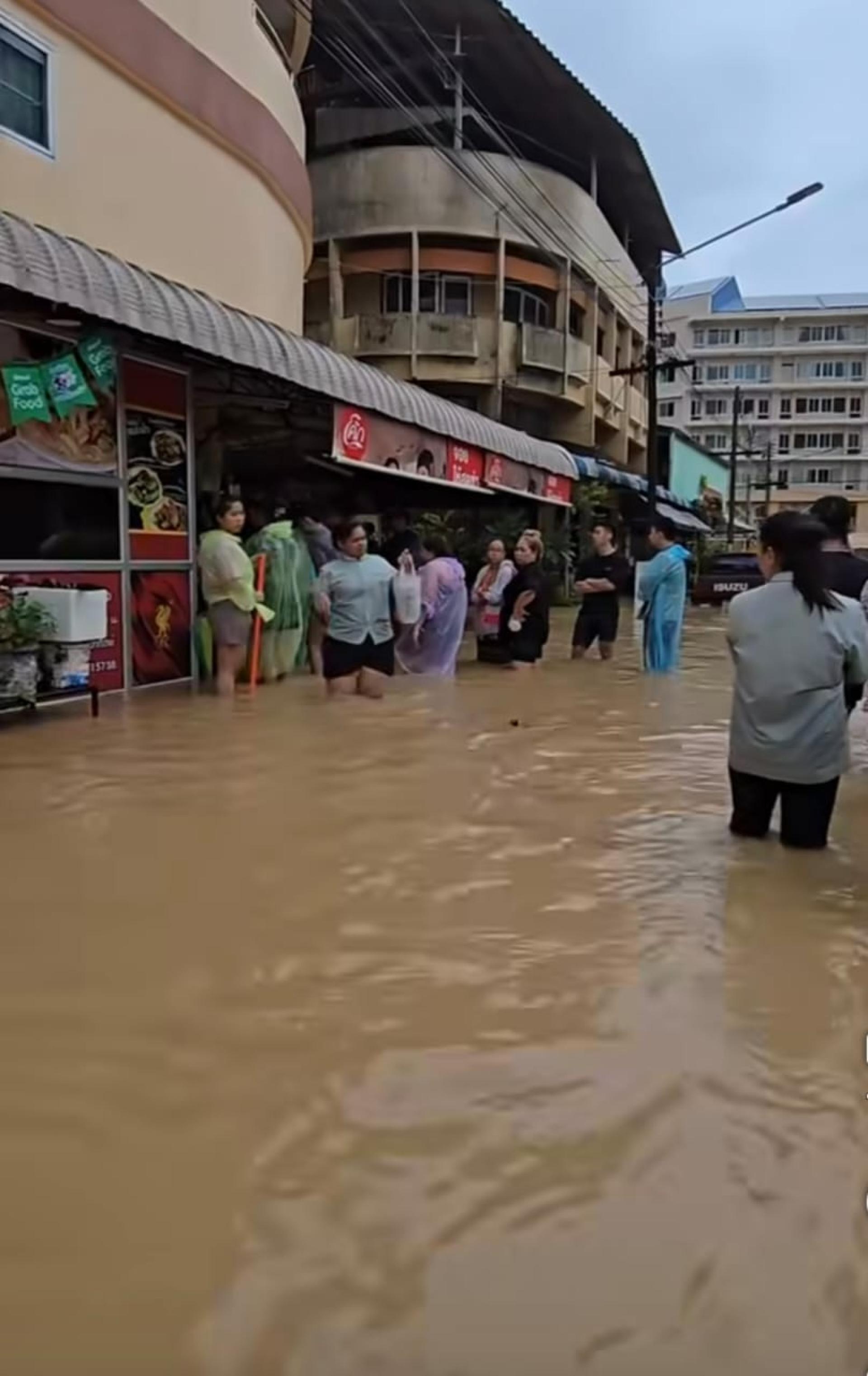 泰国合艾一餐饮业者在灾情期间免费派饭盒给受困民众，灾民在水中批队等候领饭。