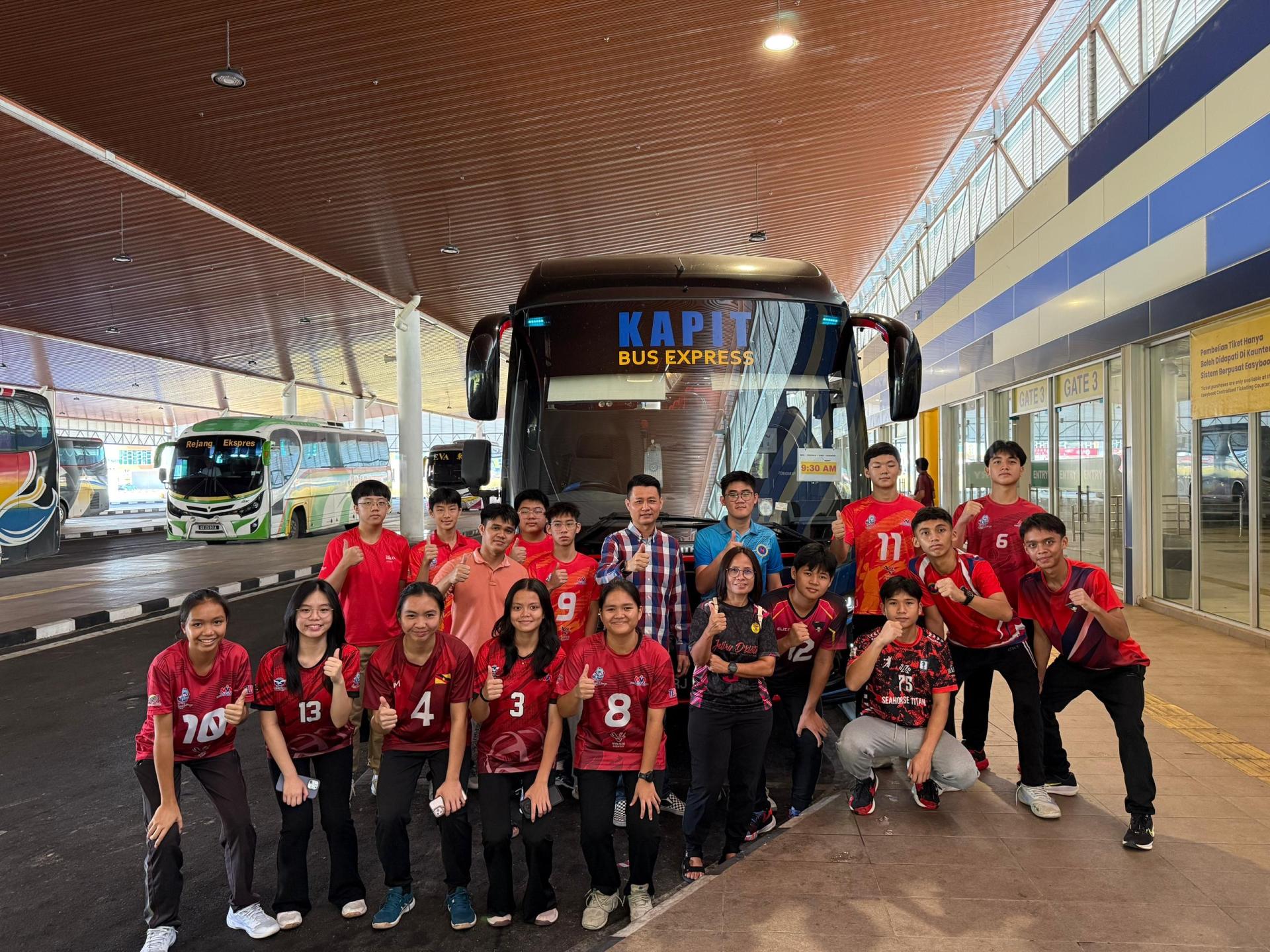 美里排总会长林思健（后排右4）和部分教练以及球员日前出发前在赞助商 Kapit Bus Express 巴士前合影。