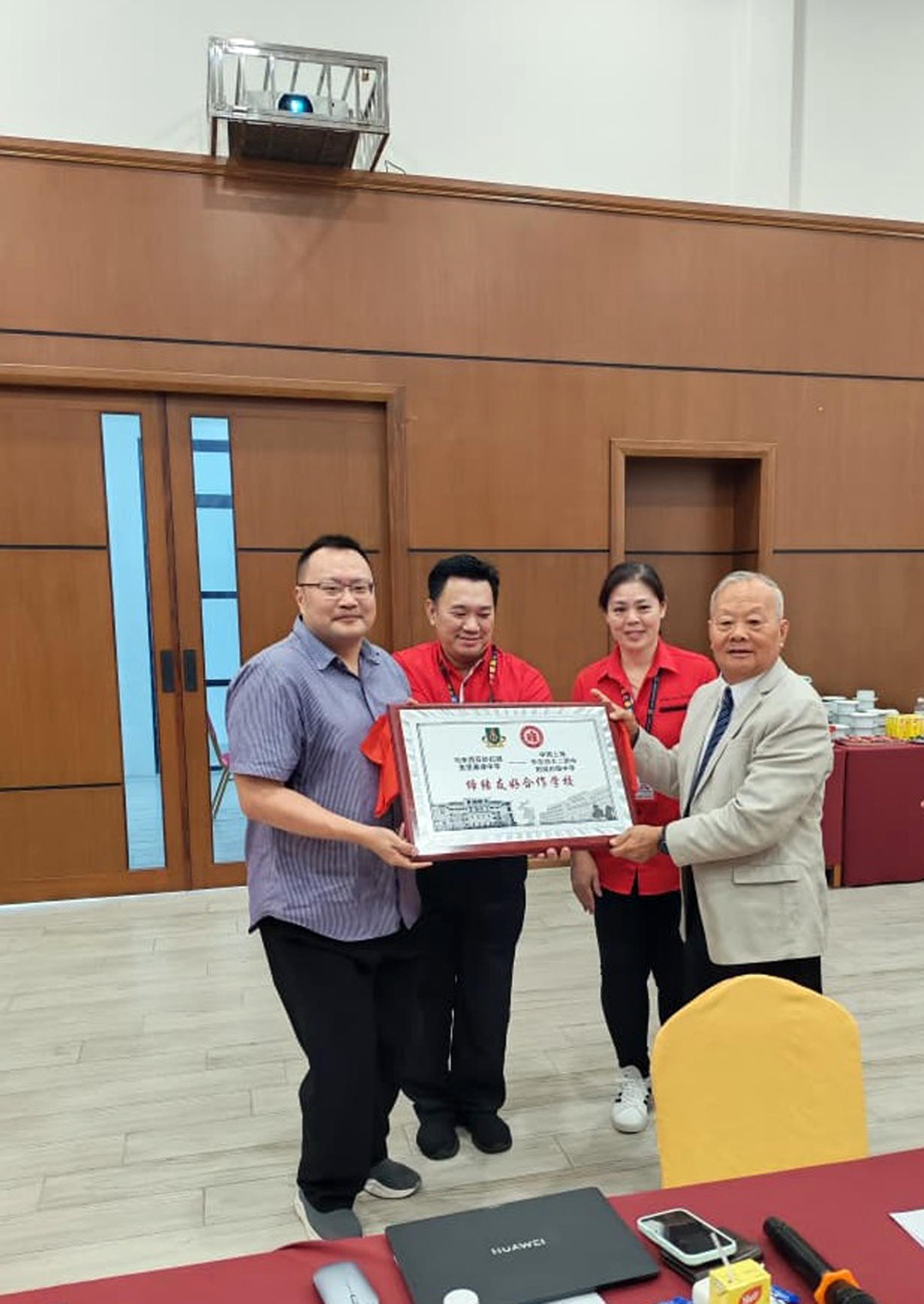 廉律中学联合董事长拿督斯里刘久健与华东师范大学国际合作与交流处副处长王素斌，以及江佩娟校长共同展示缔约牌匾。