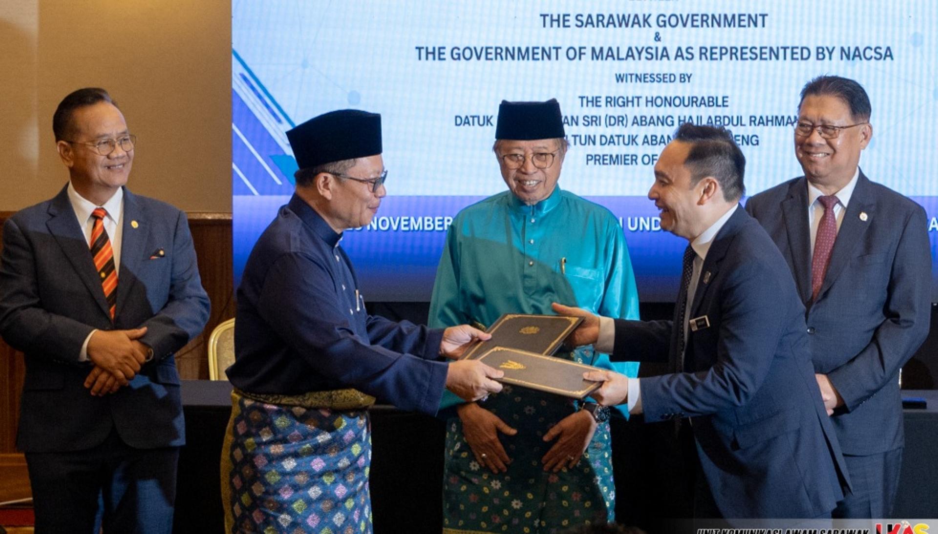 砂总理阿邦佐哈里（中）见证双方代表移交合作备忘录。