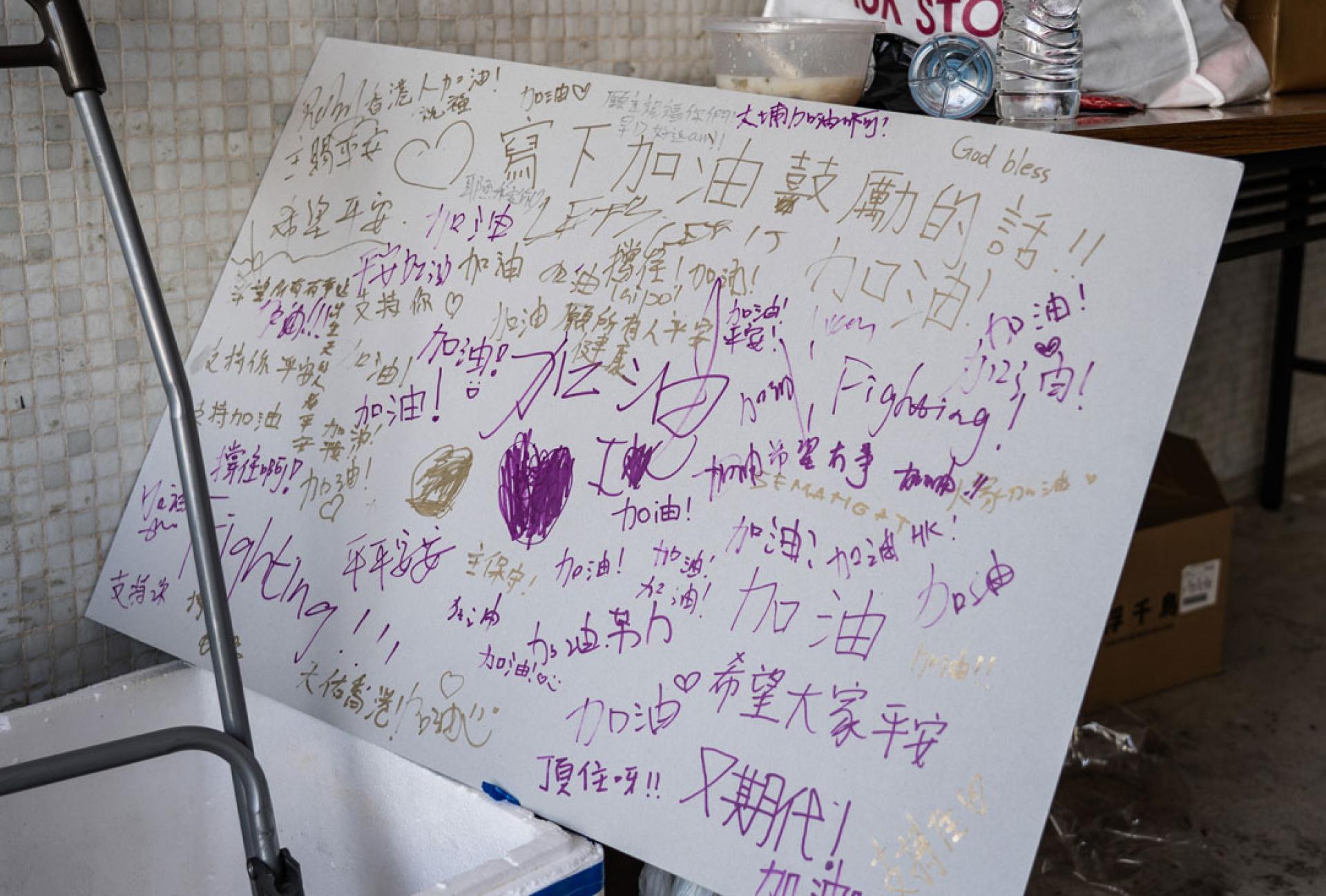 火灾现场附近的广福邨公众平台一角，摆放着写有市民鼓励祝福话语的留言板。（中新社）