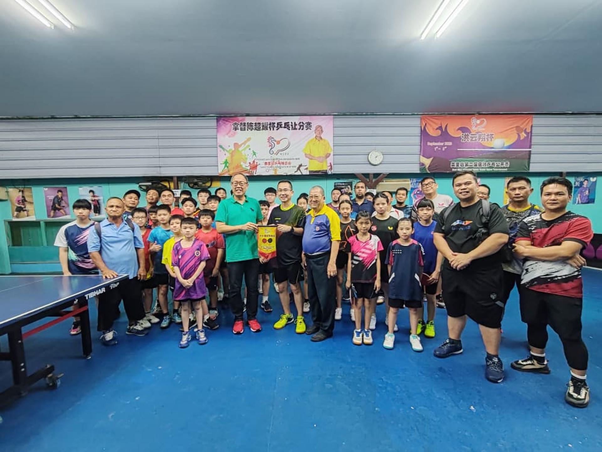 美里乒乓球总会副主席余雄星赠送锦旗予开幕嘉宾的代表甲必丹梁振林（左者）与参赛者合影。