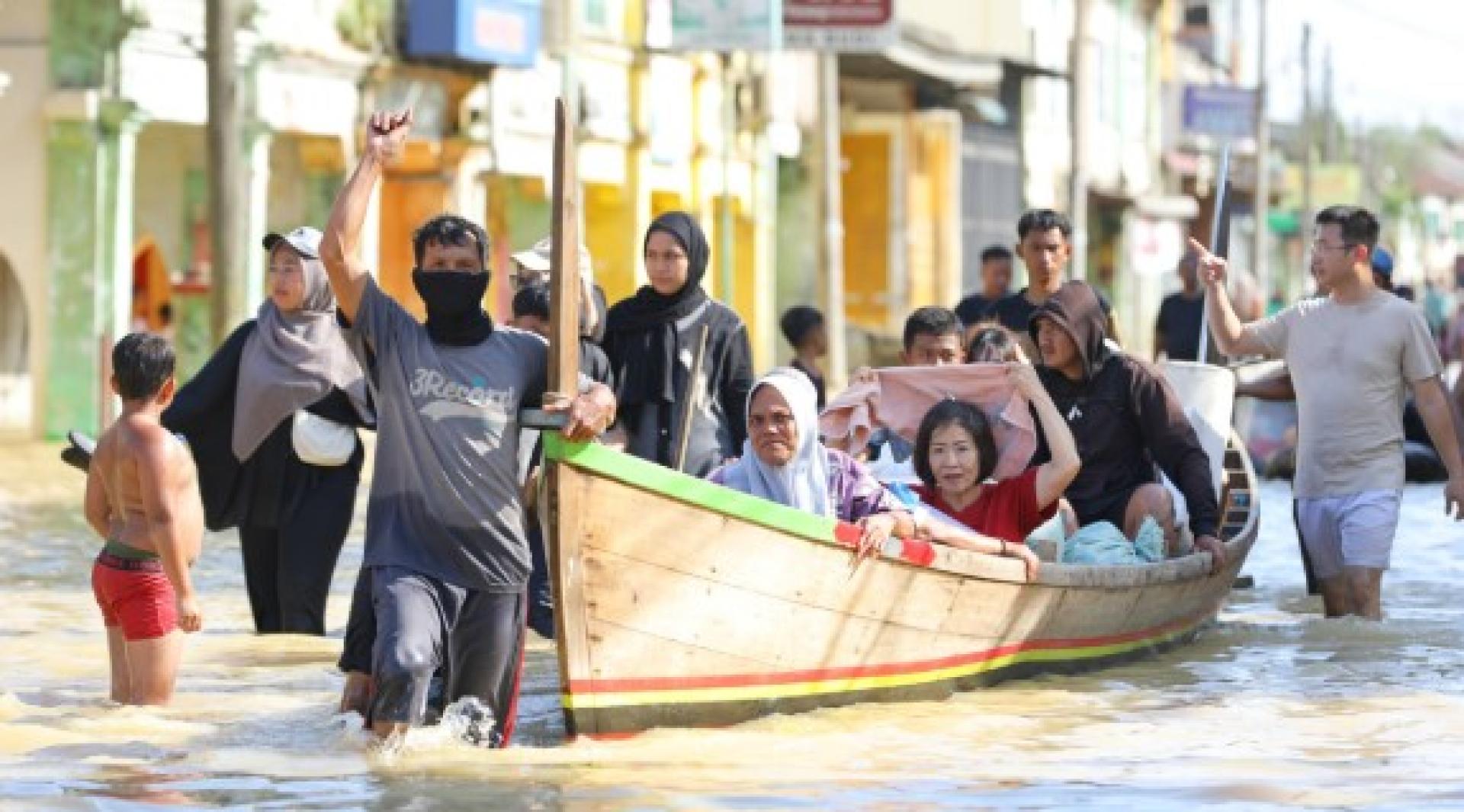 冷吉县丹戎普拉镇，遭遇洪灾的民众乘船出行。
