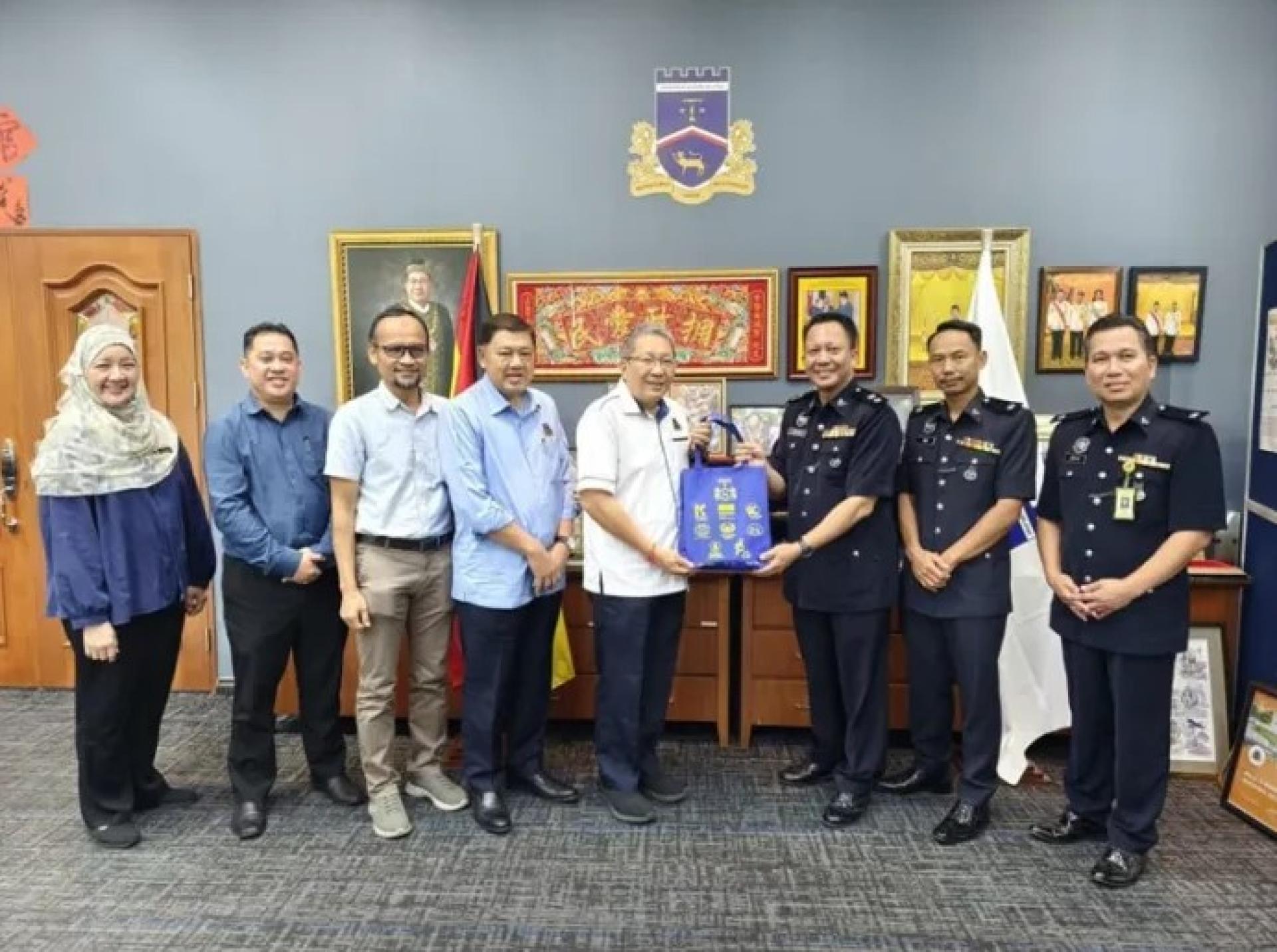 2025年12月2日，黄鸿圣（左起第五人）在古晋南市市政局总部接待礼节性拜访时，赠送纪念品予莫哈末沙菲克。