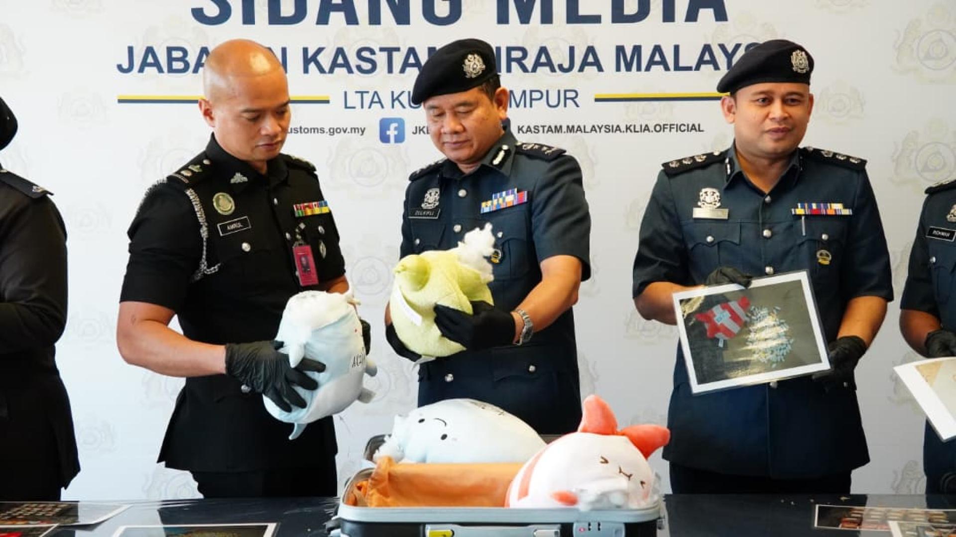 祖基菲礼（中）向官员了解“毒玩偶”的贩毒手法。