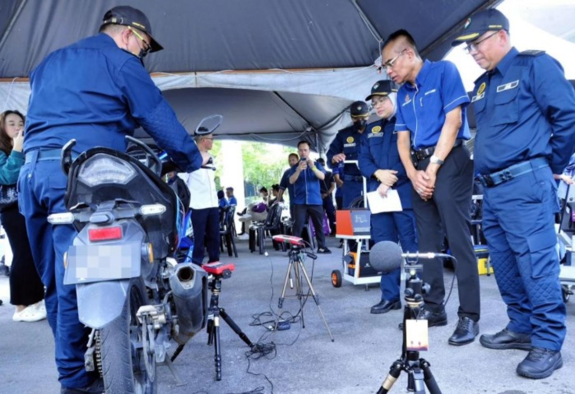 约翰（最右）与万贾法检查摩托车，参加在MBKS广场举行的国家机动车行动周启动仪式，以配合世界臭氧层日活动。