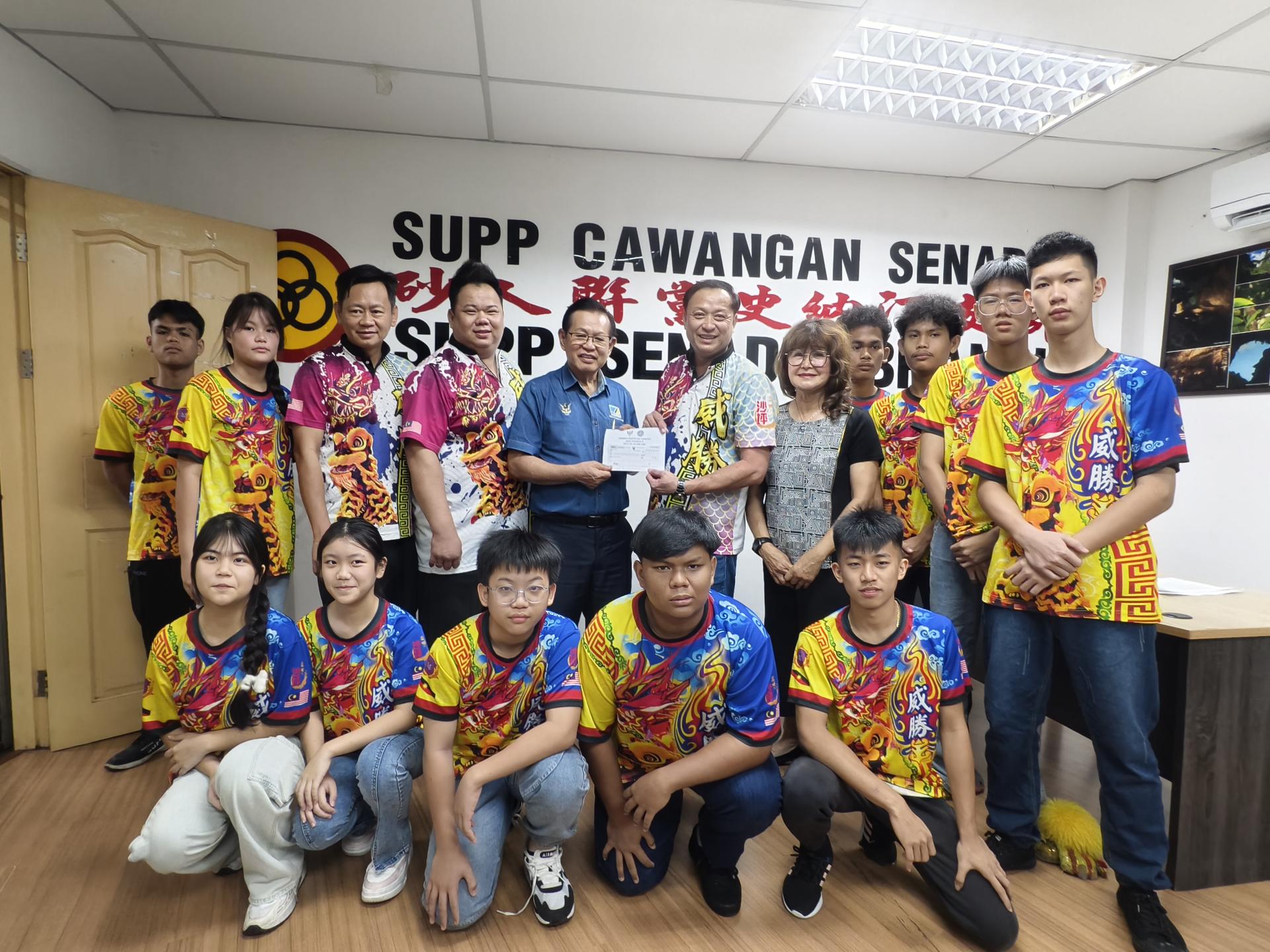 砂拉越交通部长拿督斯里李景胜（左5）移交赞助经费，由美里威胜体育会龙麒狮团主席池志达接领。