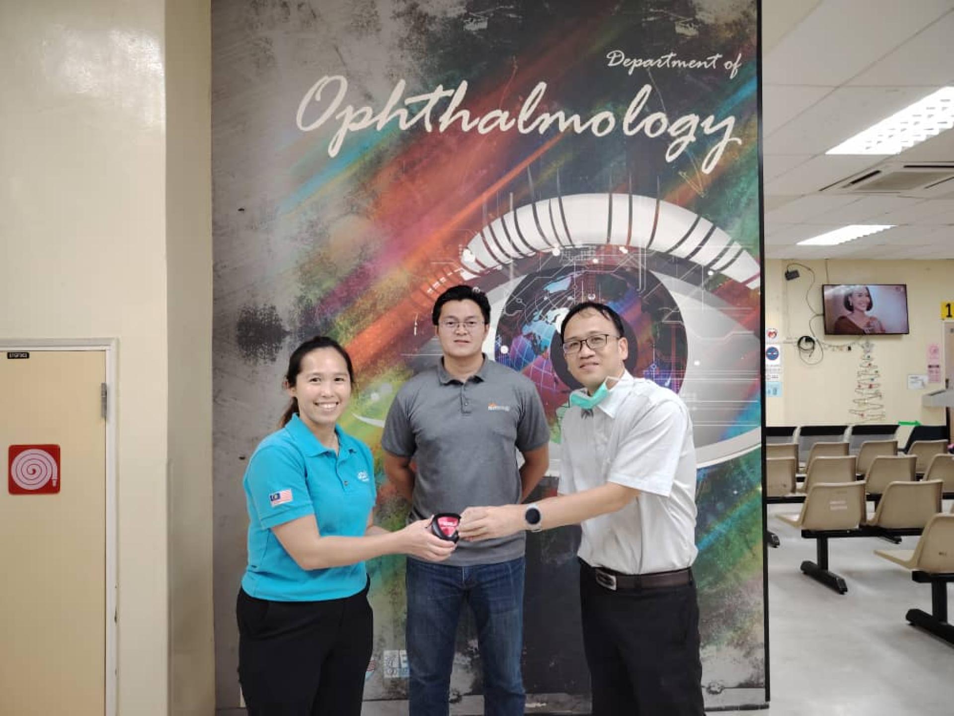 洪彩珊牙医（左）移交镜片予林子迪医生，林保光（中）见证。