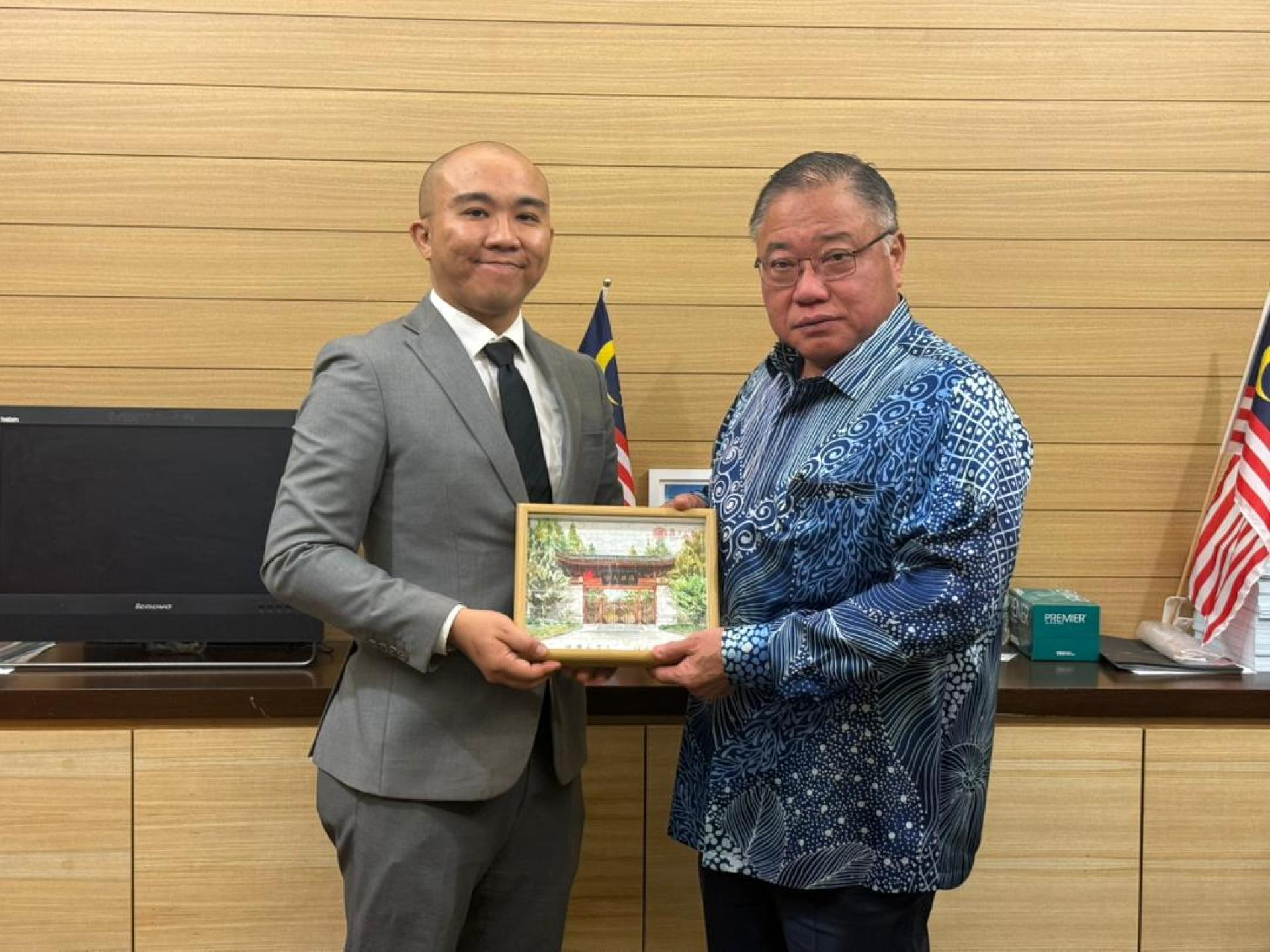 复旦大学马来西亚校友会会长黄家俊（左）向旅游部长张庆信赠送纪念品。