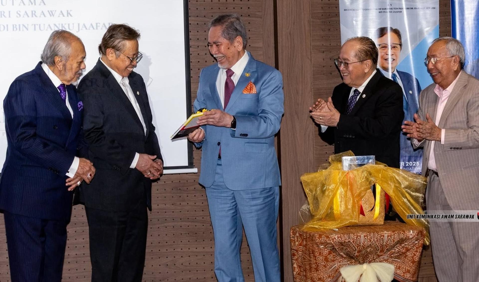 砂元首敦丕显斯里旺朱乃迪（中）在新书推介礼上，向总理阿邦佐哈里（左2）介绍该书籍。