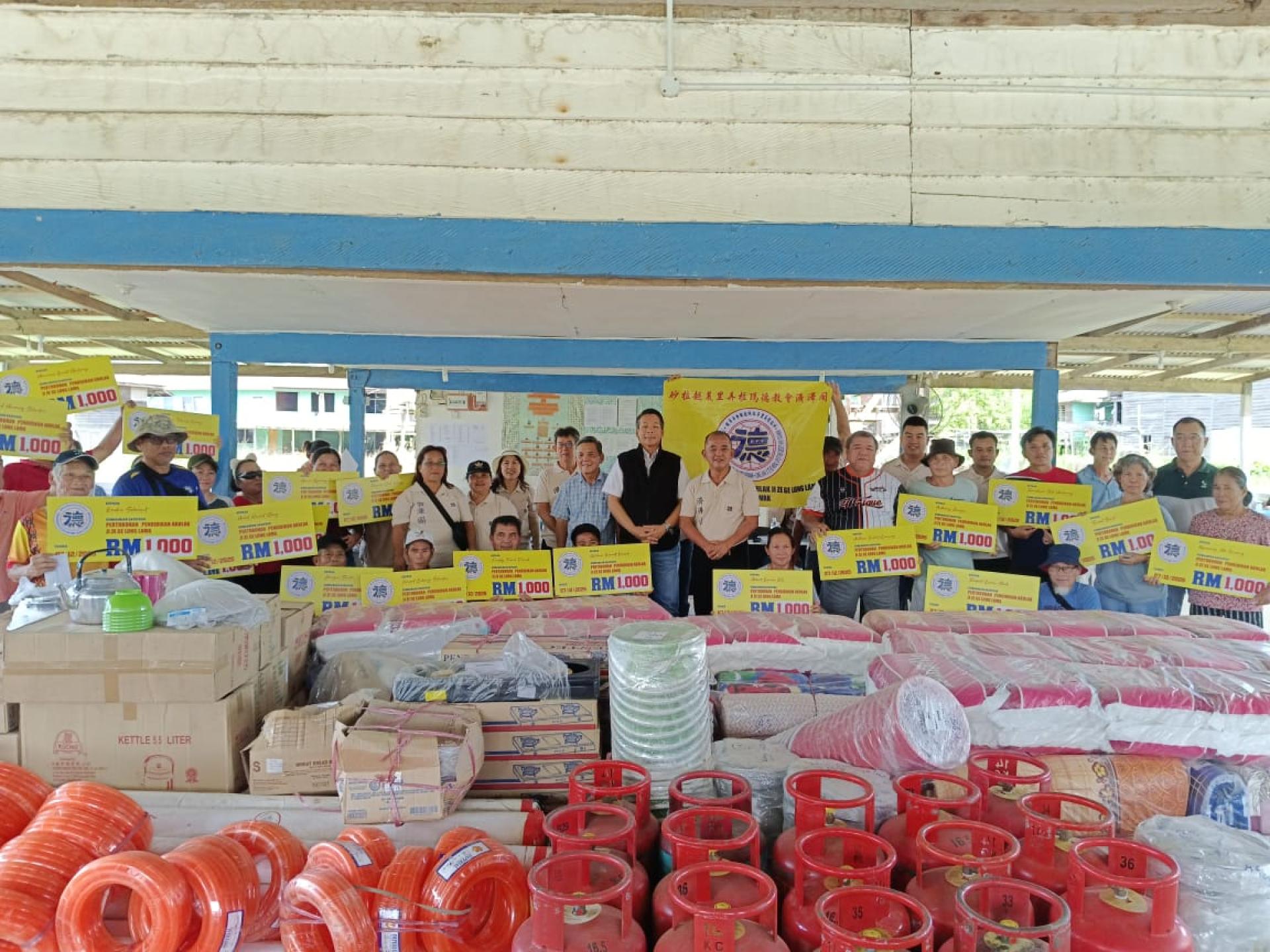 马星德教会支援行动在砂拉越美里弄拉玛德教会济泽阁协助下，昨日前往弄罗央火灾灾区，向受影响家庭移交救济品时合影。