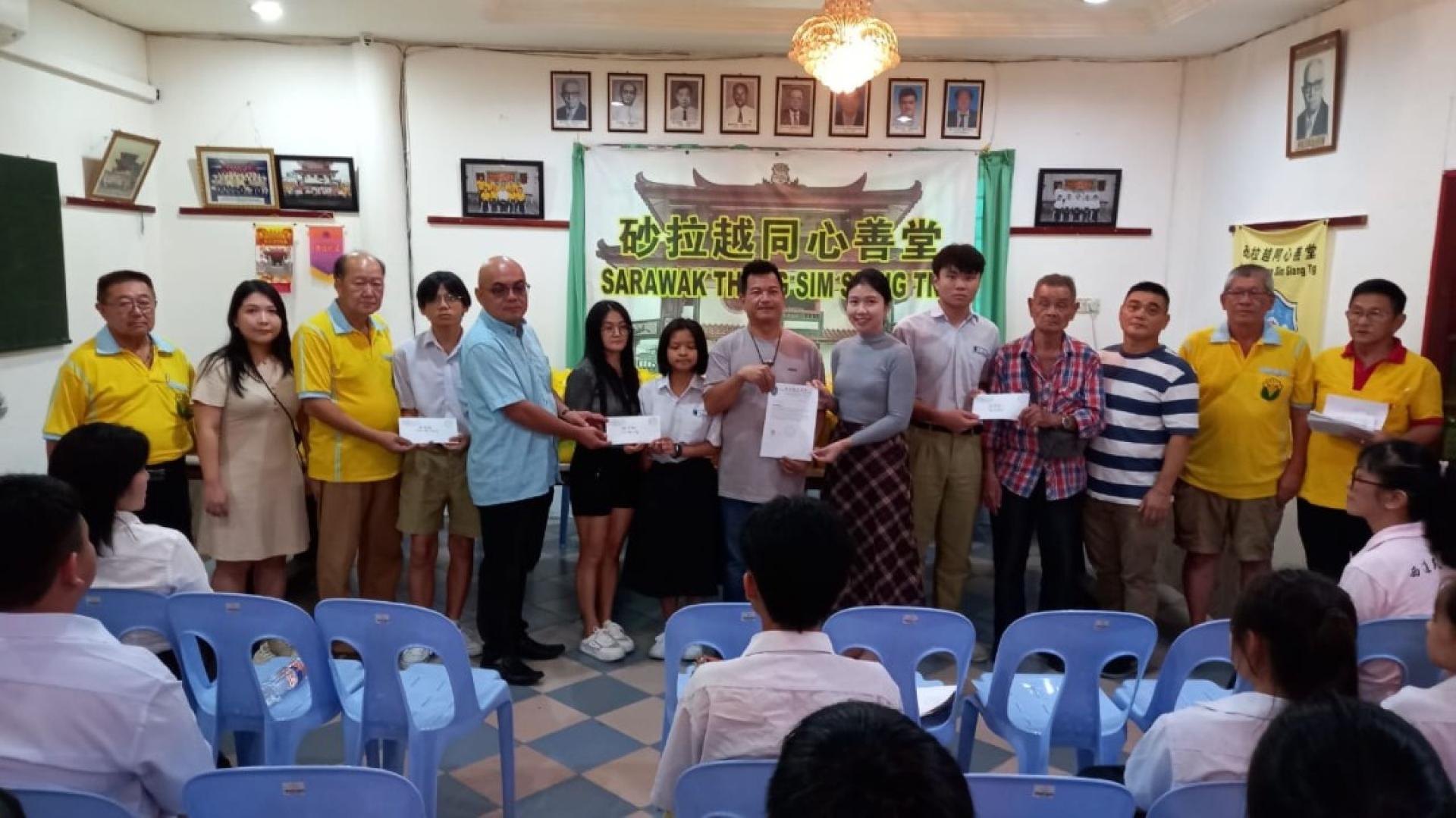 砂同心善堂主席黄国远（左3）、主宾薛华东的代表黄昭信（左5）、赞助人李友君（左8）、赞助人李锦璇（右4）移交赞助石角民立中学的3名清寒家庭高中生2026年全年学杂费，右6为石角民立中学校长赖淑珍等人。