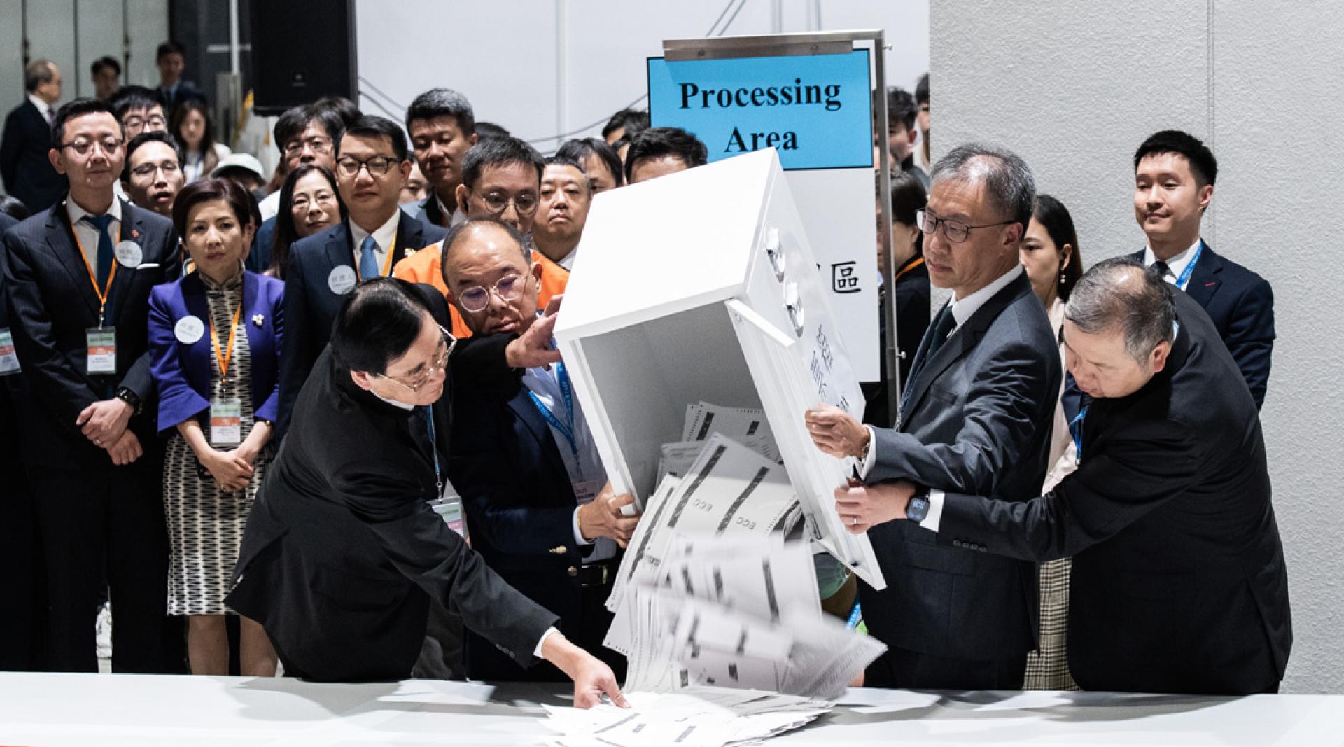 政制及内地事务局局长曾国卫（前排左二）、选举管理委员会主席陆启康（前排右二）等在位于香港会议展览中心的中央点票站倒出选票。（图：中新社）