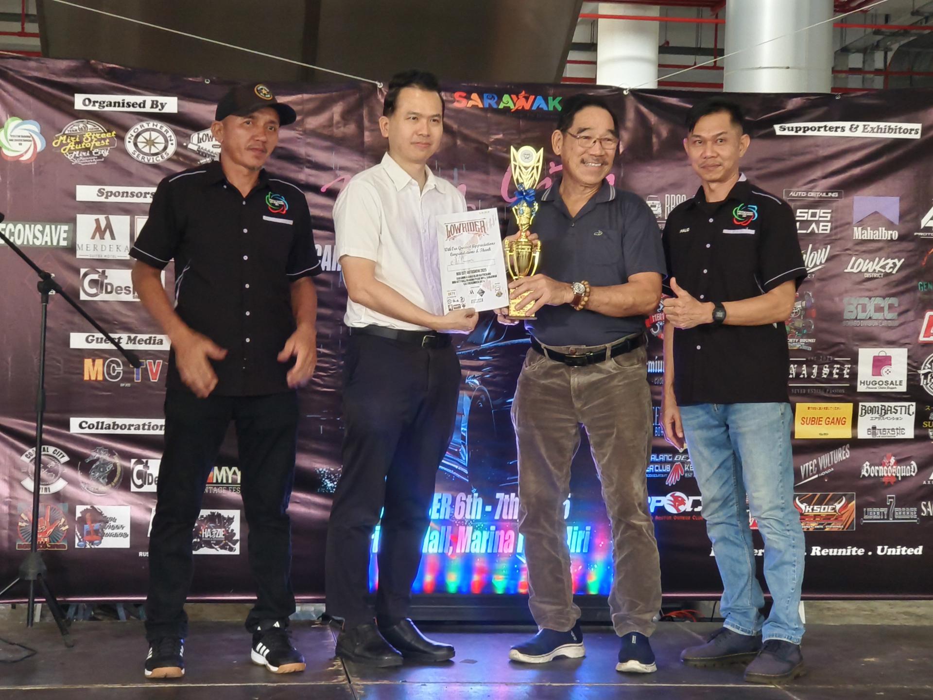 主宾拿督斯里李景胜的代表拿督刘士源（左2）在2025年第13届美里城市汽车展颁奖典礼上颁奖予其中一名得奖者。