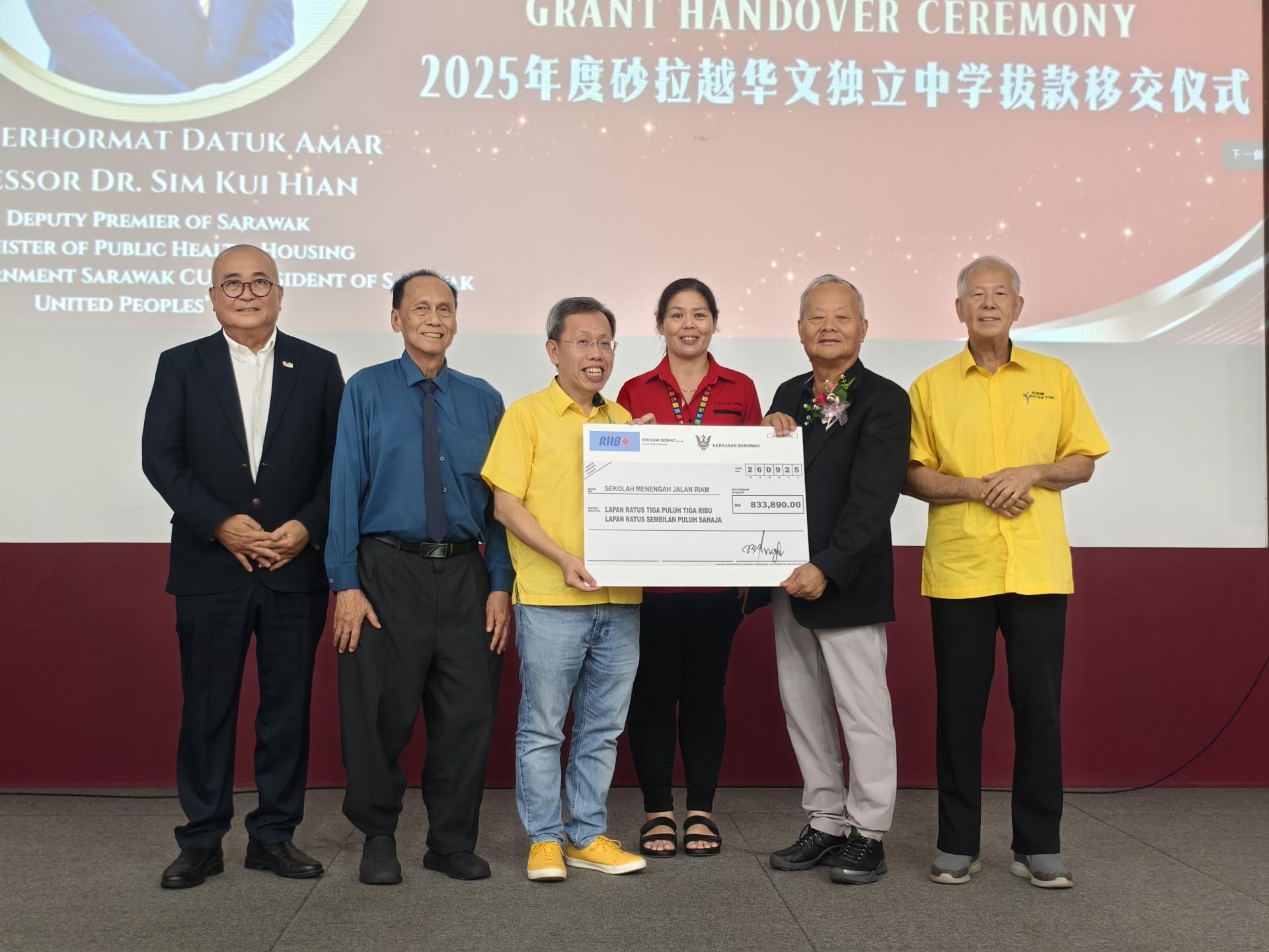 砂拉越副总理拿督阿玛沈桂贤（左3）移交2025年度砂拉越华文独立中学拨款83万3890令吉给美里廉律中学，由联合董事长拿督斯里刘久健接领。