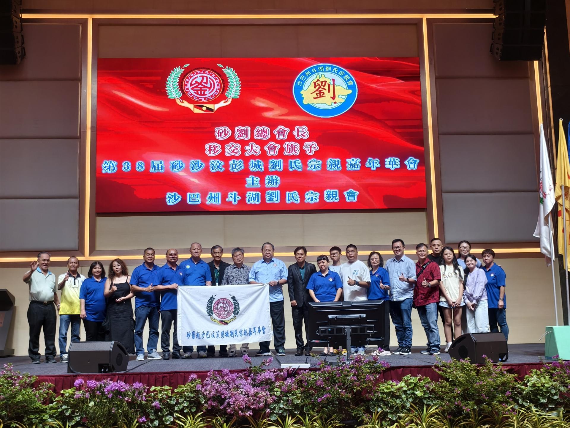 砂彭城刘氏公会联合总会总会长本固鲁刘贤远（左10）移交砂沙汶彭城刘氏宗亲嘉年华大会旗予第38届主办方沙巴州斗湖刘氏宗亲会，由主席刘月德（左6）接收。左7起为沙巴州斗湖刘氏宗亲会会长刘永祥、民都鲁彭城刘氏公会会长刘仁陆、闭幕主宾兼民都鲁彭城刘氏公会名誉会长拿督斯里刘贤文，以及民都鲁彭城刘氏公会主席兼筹备会主席刘世伦（左11）。