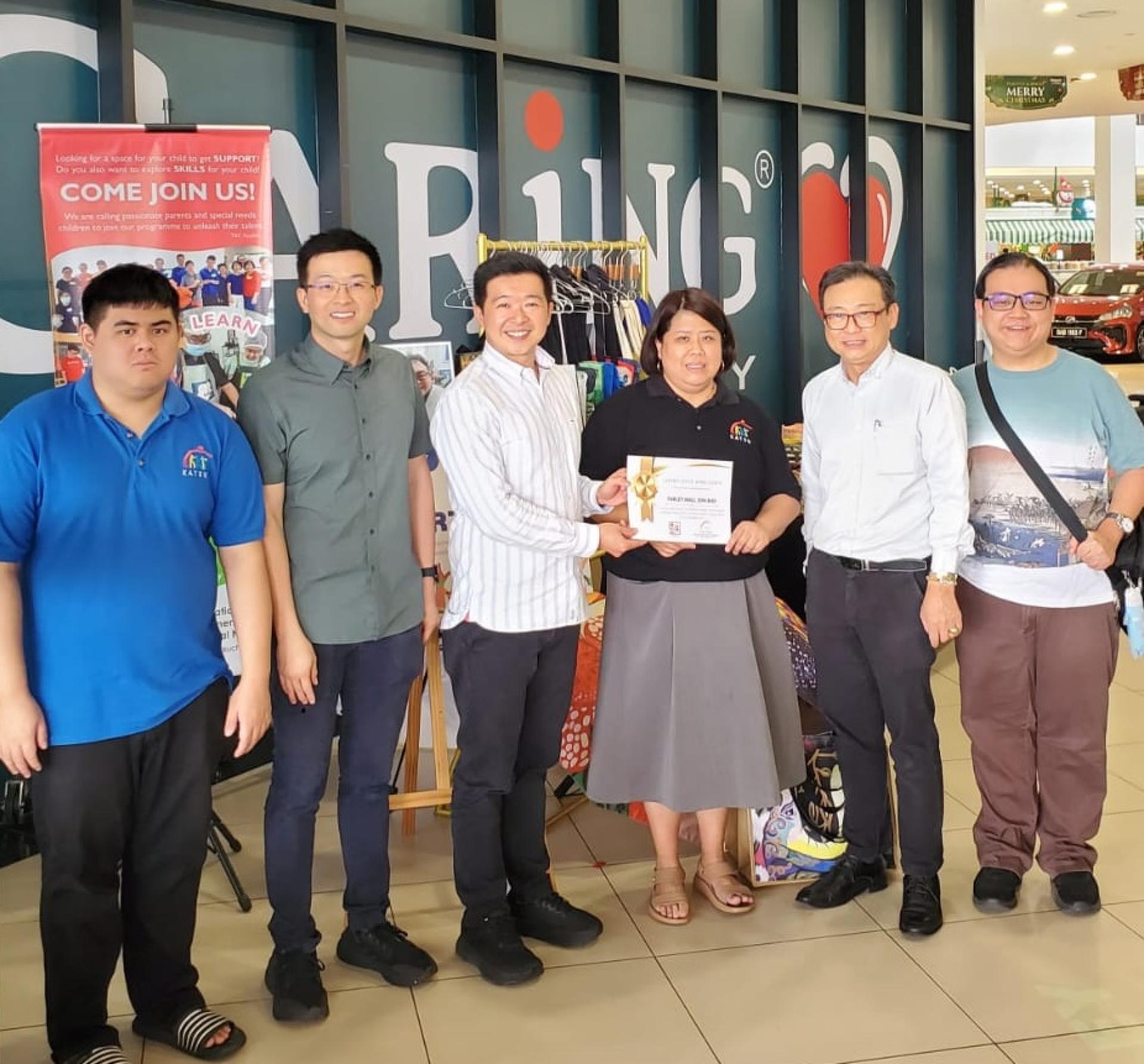 古晋特殊群体潜能发展协会会长林美玉（右3）颁发感谢状予华利的刘奕陞（左3）及刘宜谚先生（左2）。出席者还包括拿督沈坚石（右2）、沈登豪（右1）及李启源（左1）。