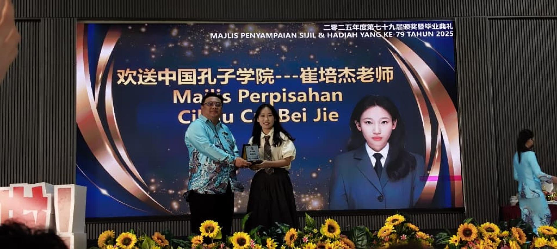 美里罗东中华公学校长赖昭恬（左起）赠送纪念品感谢崔倍杰老师在校期间合作推动的非华裔学生学习华语计划。