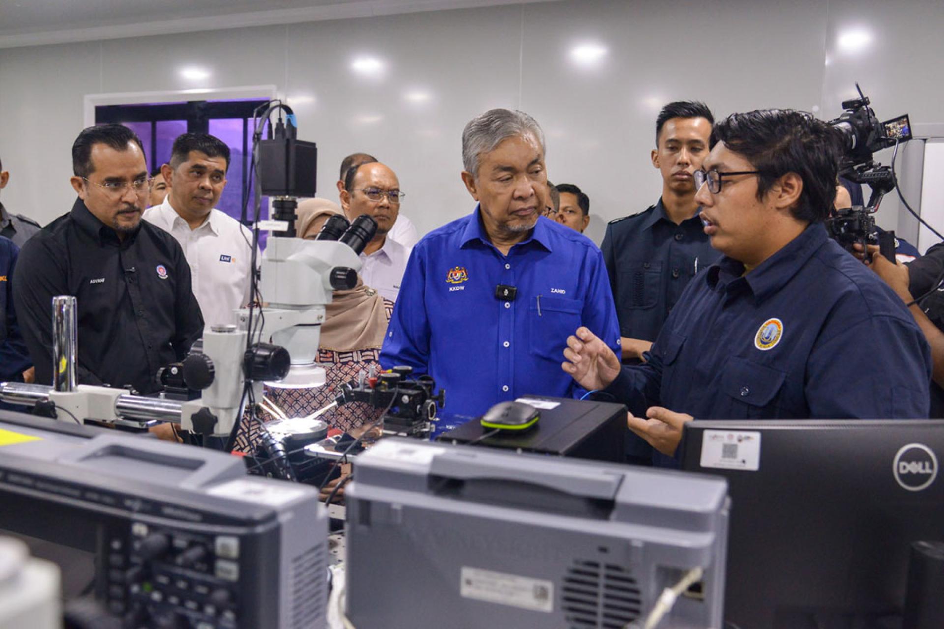 阿末扎希聆听电子工程学生讲解有关身份证集成电路或芯片的内容。