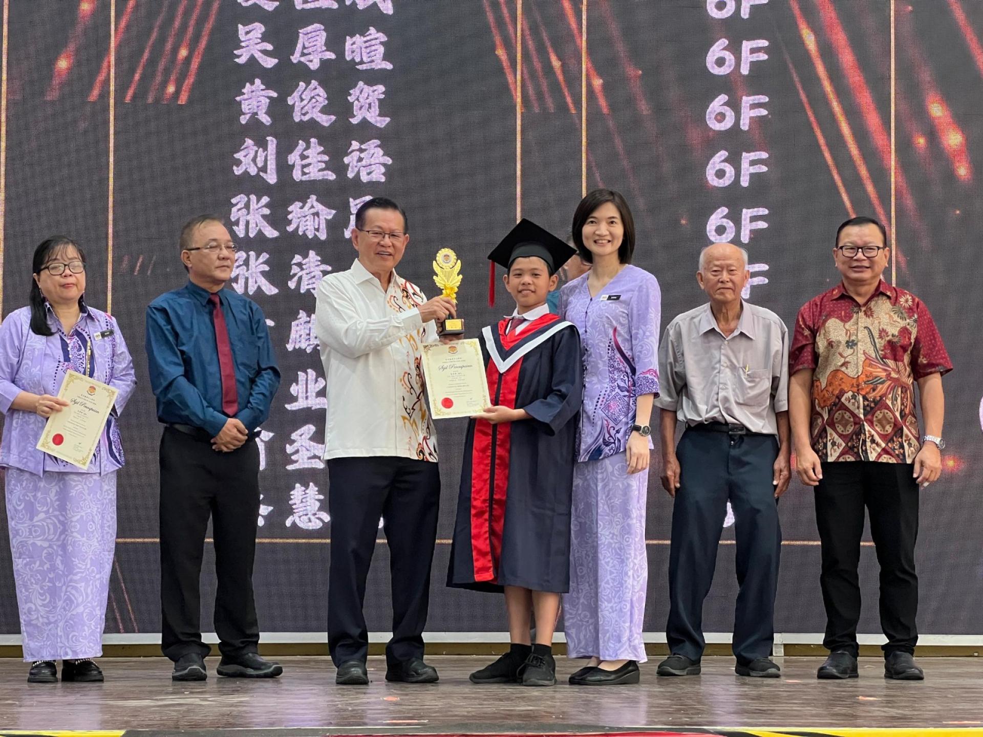 李景胜（左三）颁发六年级优等学朮奖第一名予夏恒斌（右四）。