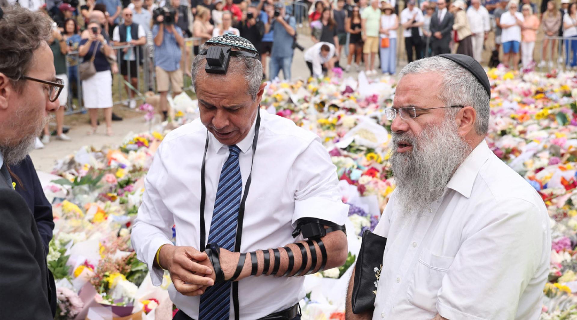 以色列驻澳大使迈蒙（中）16日在悉尼邦迪海滩悼念邦迪海滩枪击案遇难者。