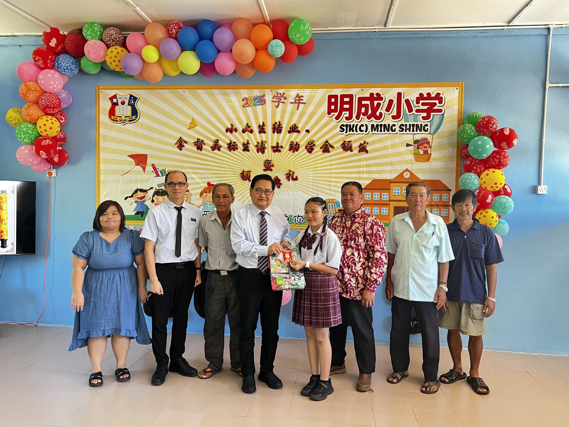 拿督吴标生（左4）颁发200令吉奖金和校方准备的礼物予明成小学2025年度模范生陈芯妤（左5）。