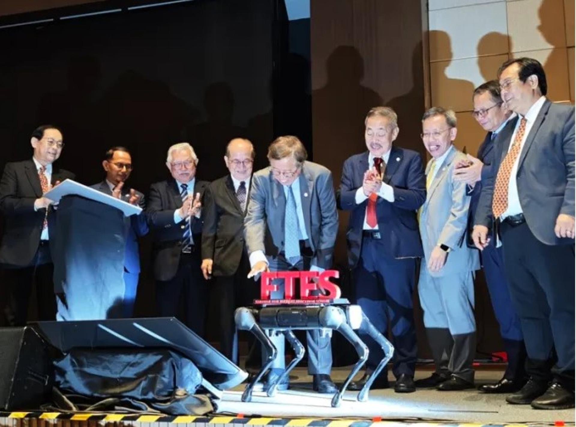 阿邦佐哈里在机器人狗上放置字母“F”，完成“FTES”字样，为砂拉越免费高等教育计划主持推介仪式。