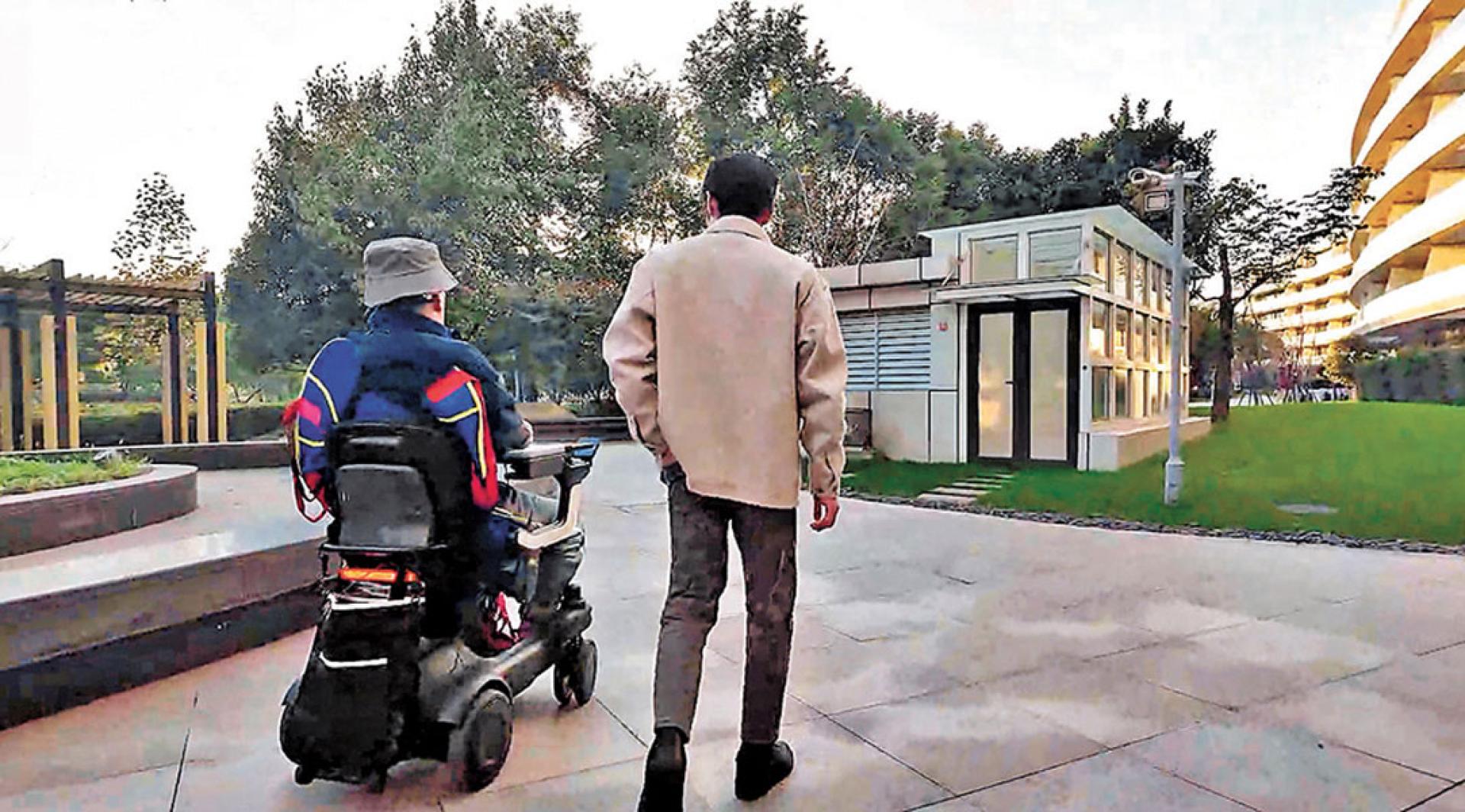 四肢瘫痪患者（左）通过脑智卓越中心等单位研发的脑机接口系统意念控制轮椅在小区自如散步。