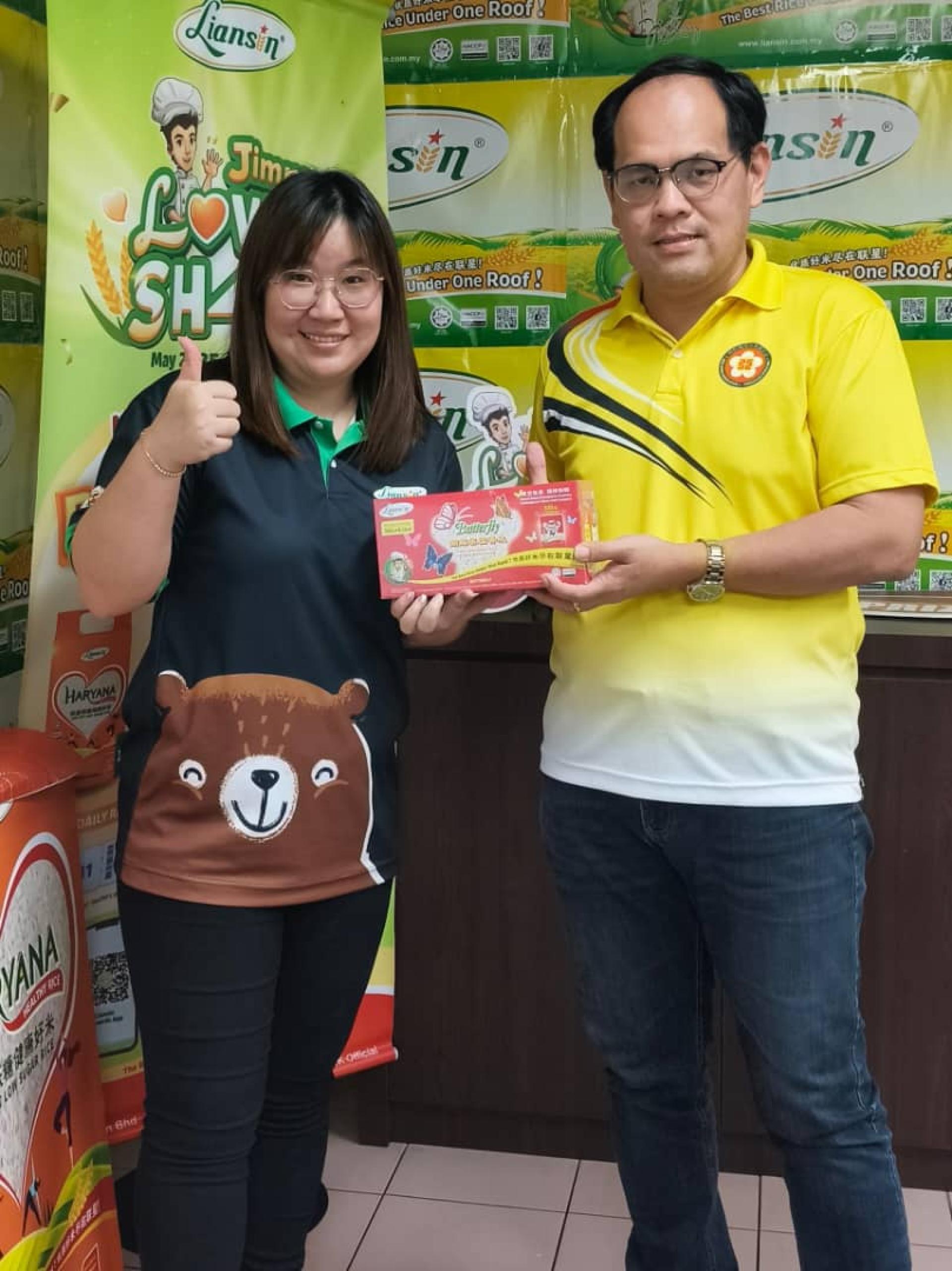 同成发稻米贸易有限公司市场发展执行员丘紫霞（左）日前移交赞助品予美里客家公会青年团团长杨万勇。