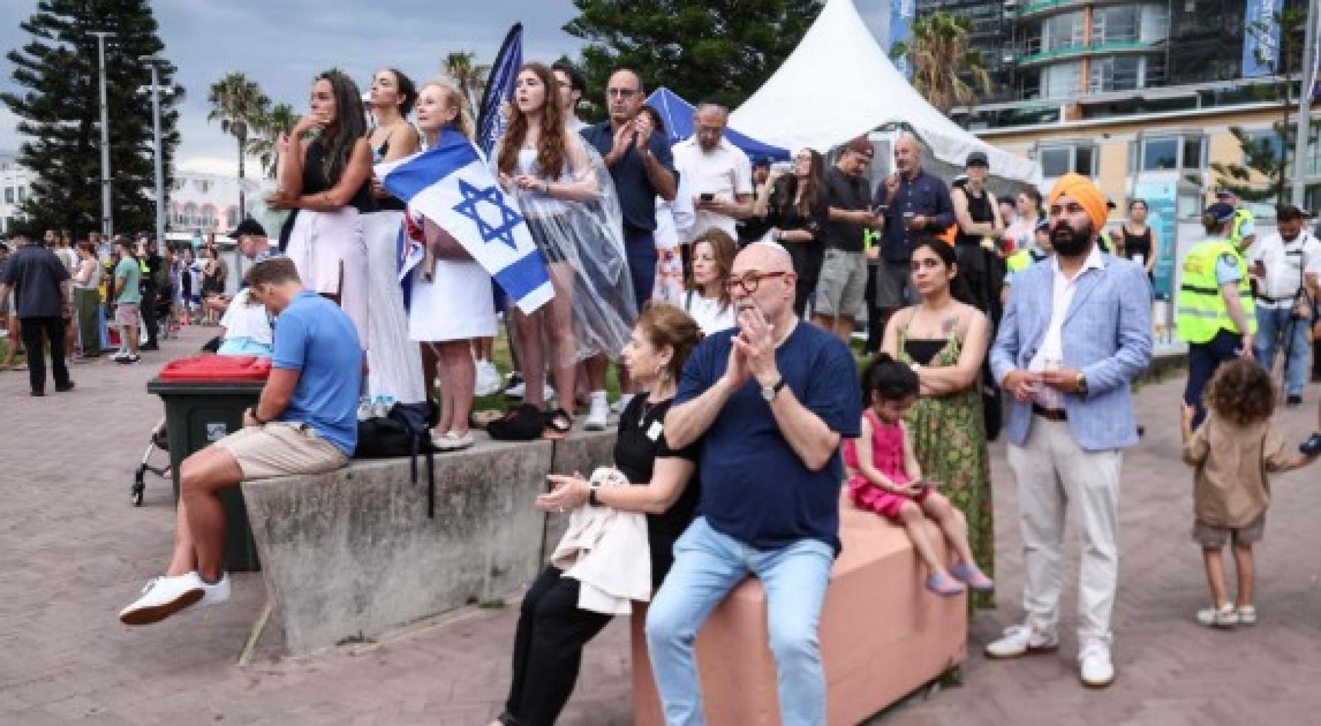 人们21日到悉尼邦迪海滩参加枪击案遇难者追悼会。