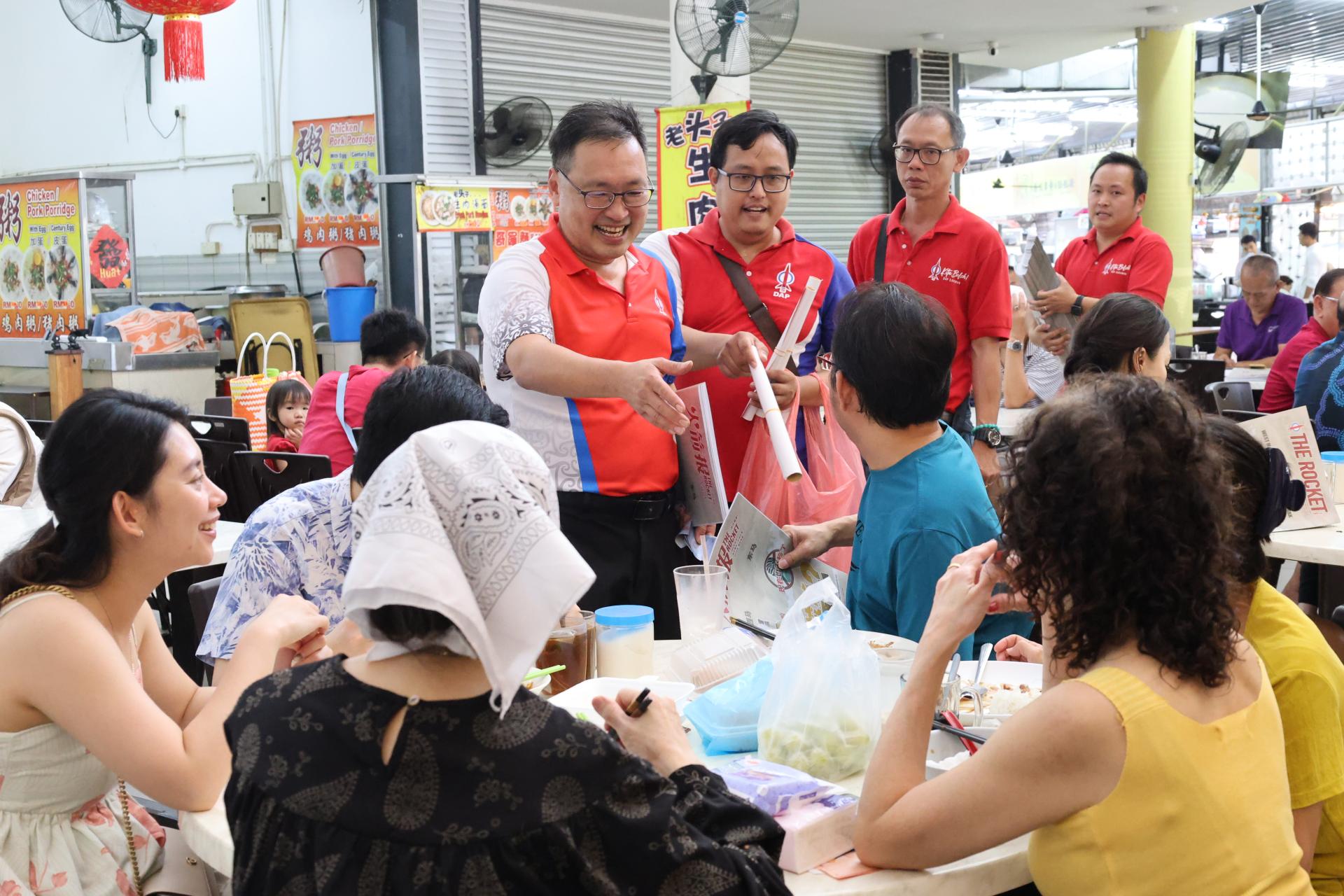 砂行动党主席兼国州议员张健仁（中）在圣诞节与团队走访101和Green Height商业中心销售《火箭报》及派发2026年年历。