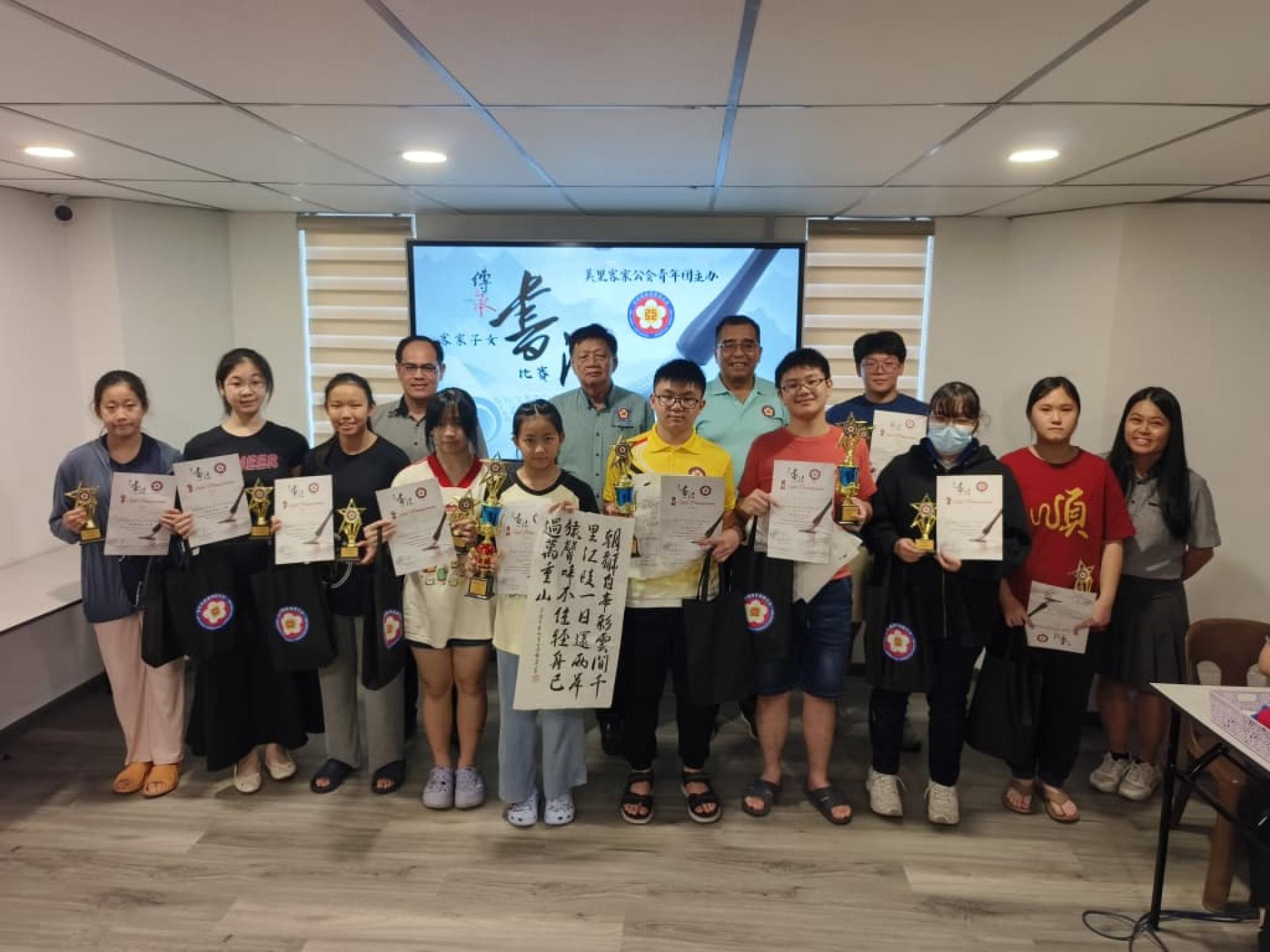 美里客家公会青年团“2025年客家子女传承书法赛”中学组颁奖礼合影。后排左起为青年团团长杨万勇、副主席黄能喜、秘书长杨春德，以及筹备会主席刘丽美（右）。
