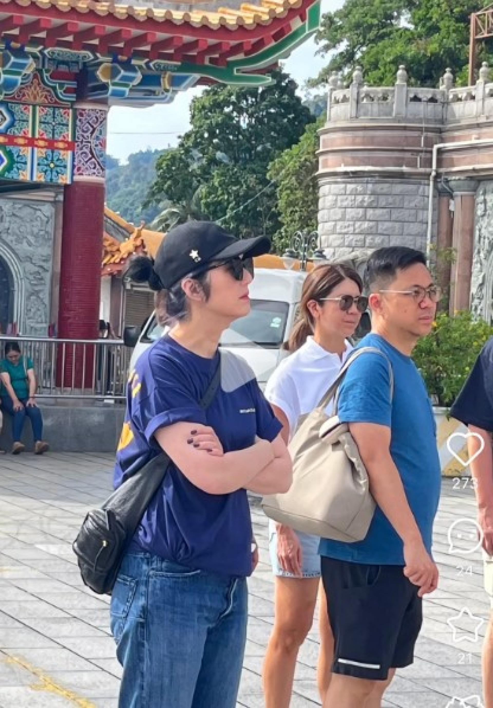 杨千嬅戴着鸭嘴帽和墨镜，身穿蓝色T恤搭配牛仔裤现身槟城极乐寺。