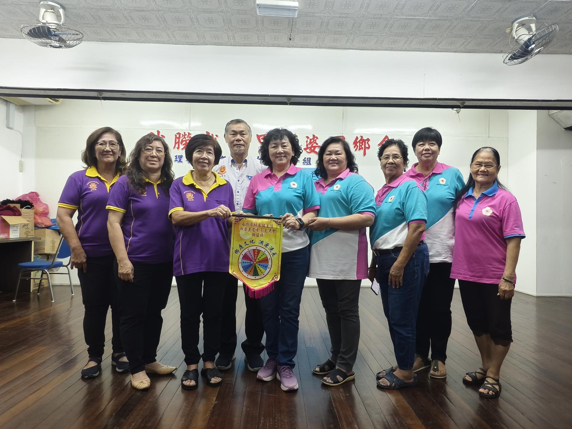 美里河婆同乡会妇女组主任蔡素芳（左3）在组委陪同及会长蔡传创（左4）见证下，移交13乡属美食分享交流会锦旗予下一届主办乡属，由美里嘉应五属同乡会妇女组主任古秋英（右5）及组委一同接领。