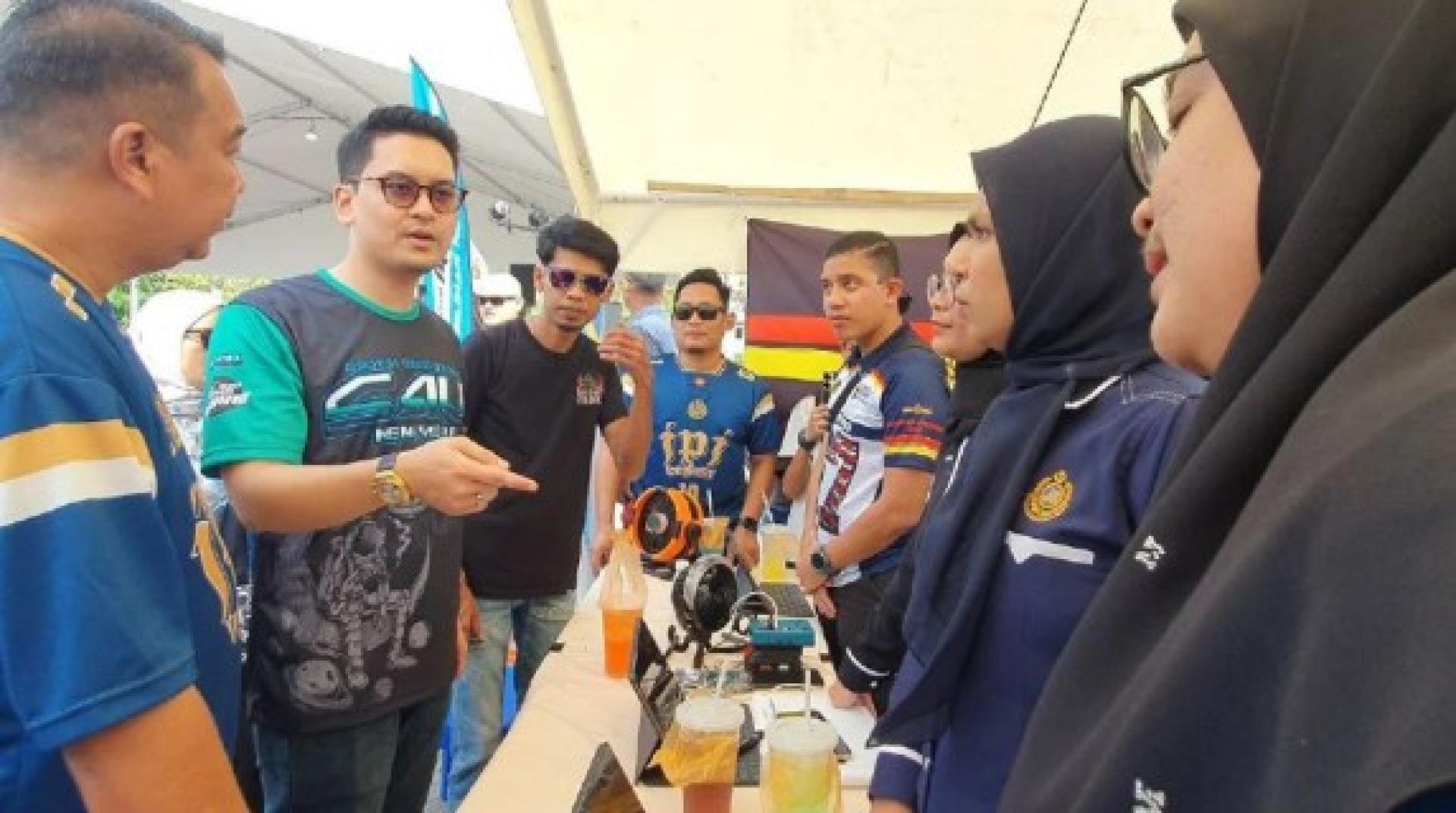 莫哈末道菲（左2）出席“北方子弟休闲大型聚会”活动，与展览区工作人员交流。