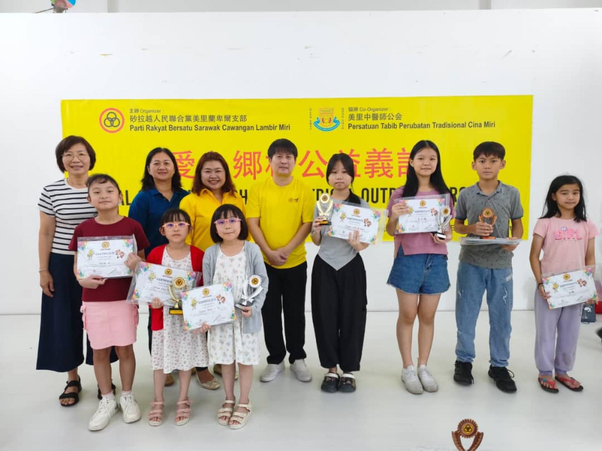 2026月历征画比赛优胜者合影。左起为都九政小校校长刘淑慧，峇甘中华公学校长林淑芬，筹备会主席李佩佩，及支部主席王智义。