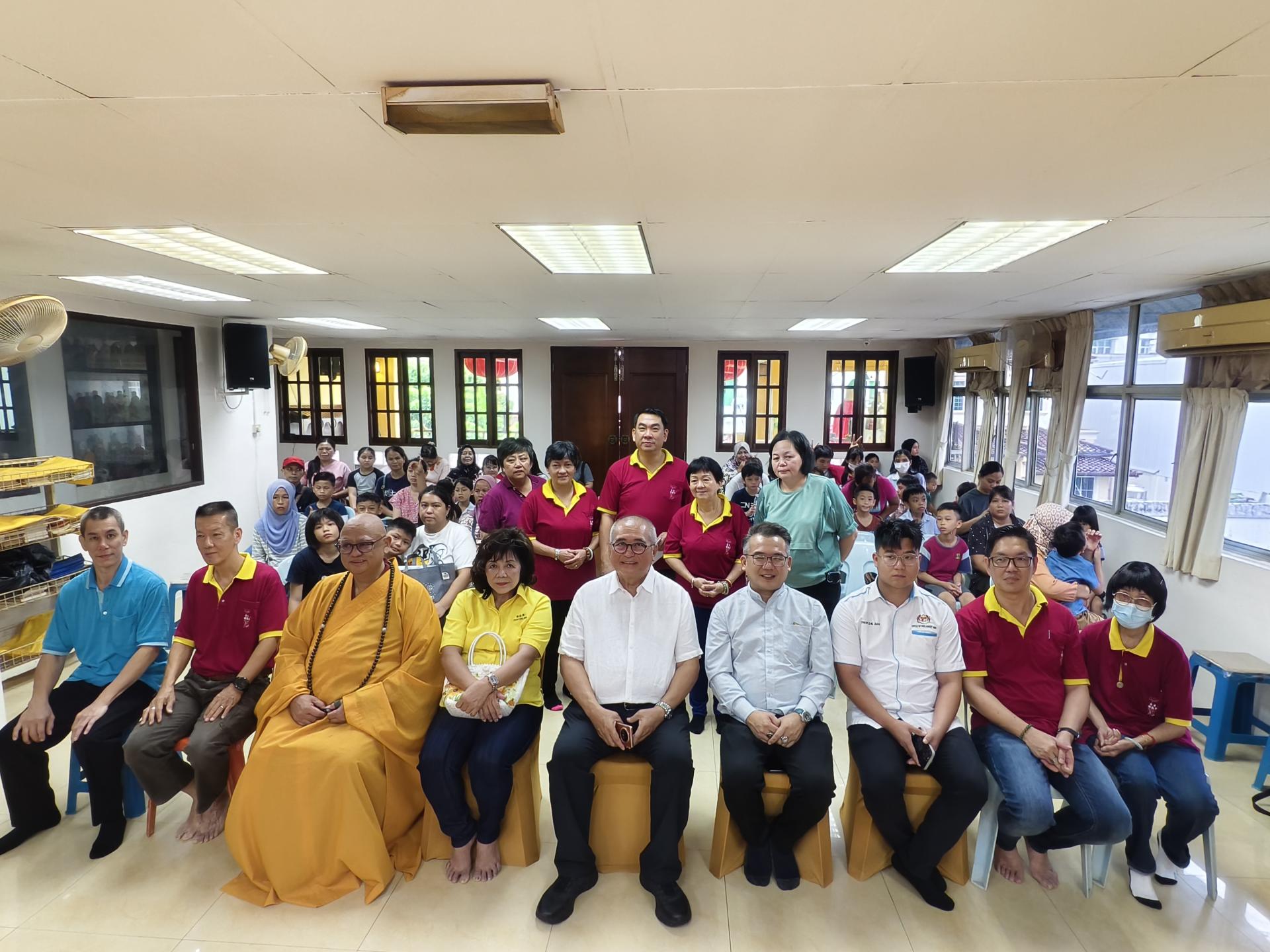 嘉宾们与部分受惠者在活动上合影。左3起为美里佛教会主席释圣林法师，砂旅游部副部长拿督陈超耀的代表甲必丹陈彩萍，美里市长俞小珊，砂交通部长拿督斯里李景胜的代表美里市议员熊千雨，联邦旅游、艺术及文化部副部长赵俊文的代表邹梓建，以及美里佛教会财政罗金强。