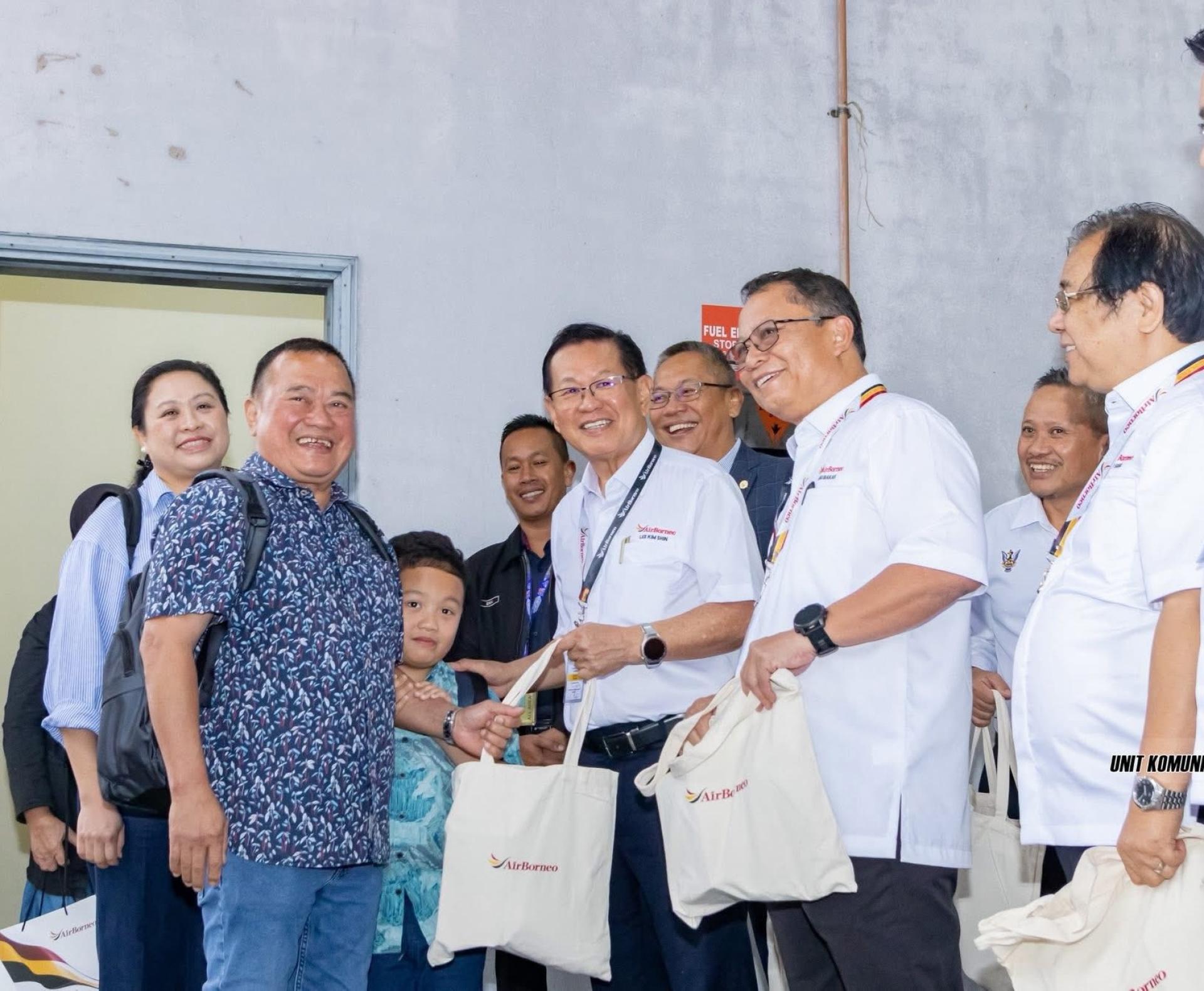 拿督斯里李景胜（右3）派送纪念品给乘搭婆罗洲航空的乘客。